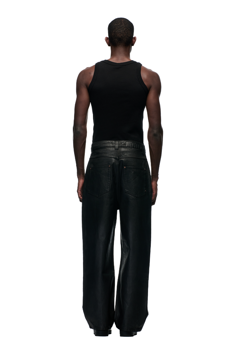 A person with short hair is seen from behind, wearing a black sleeveless top and 6PM's WAX COATED DENIM BLACK jeans with metal buttons, set against a plain light gray background.