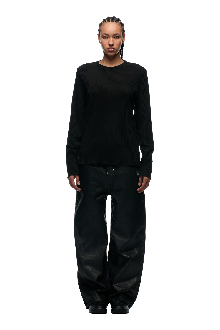 A person with braided hair faces forward, wearing the 6PM 6PM+ RIBBED LS BLACK top and oversized black pants, against a plain white background.