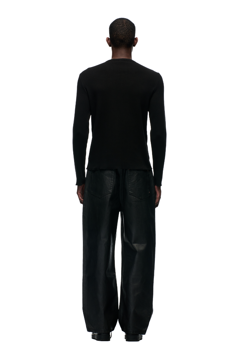 A person faces away, wearing the 6PM+ RIBBED LS BLACK top by 6PM paired with loose black pants. The backdrop is a plain light gray.