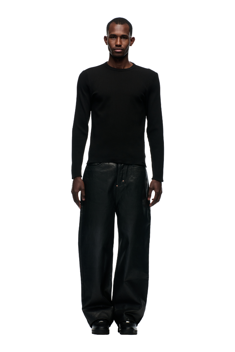 A man faces forward against a plain white background, wearing the 6PM 6PM+ RIBBED LS BLACK top, paired with loose, wide-leg black pants and black shoes.