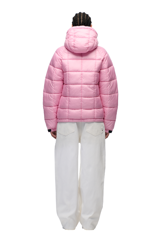 A person faces away, wearing the 6PM LIGHT PUFFER JACKET RECTANGLES PINK with an adjustable hood and loose white pants, set against a plain white background.