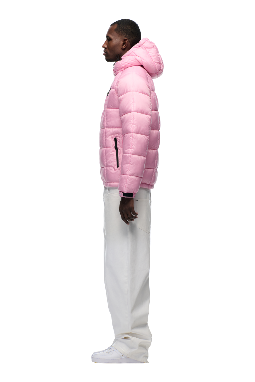 A man in profile wears the 6PM LIGHT PUFFER JACKET RECTANGLES PINK with an adjustable hood, paired with white pants and white sneakers, standing against a plain white background.