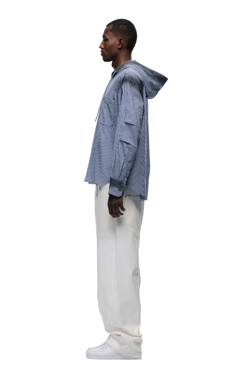 A man in profile against a white background wears the 6PM HOODED DRESS SHIRT DEEP SEA BLUE/WHITE, paired with off-white pants and white sneakers.