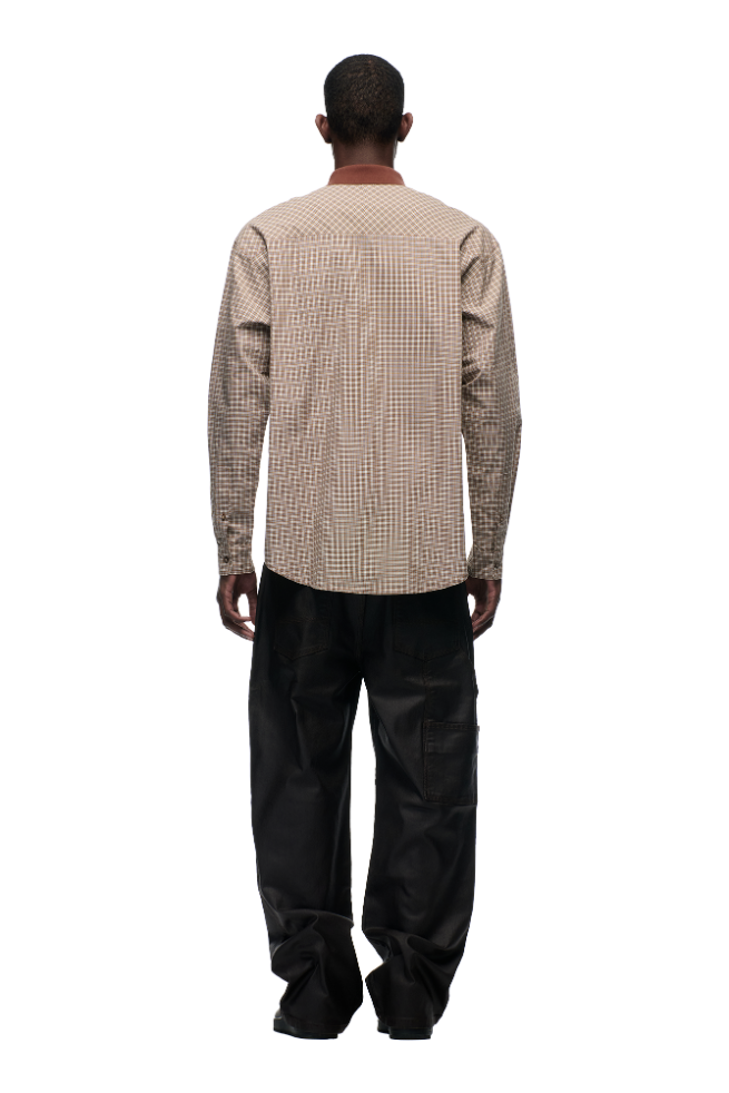 Against a plain white background, a person faces away wearing the 6PM POLO COLLAR SHIRT COCOA BROWN—a beige and brown checked cotton shirt with horn buttons—paired with loose-fitting black pants.