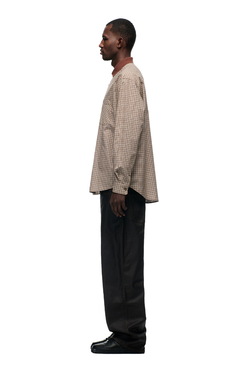 A man stands in profile against a white background, wearing the 6PM POLO COLLAR SHIRT COCOA BROWN, paired with loose black pants and black shoes.