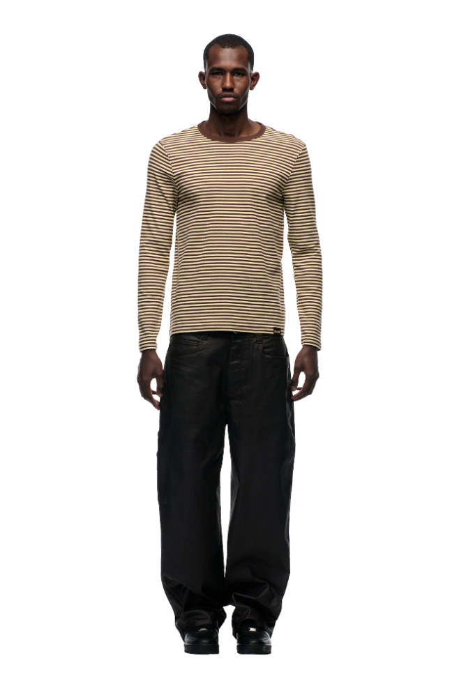 A man faces forward wearing the 6PM STRIPED RIBBED LS DARK HAZELNUT top and loose black pants with black shoes, set against a plain light background.