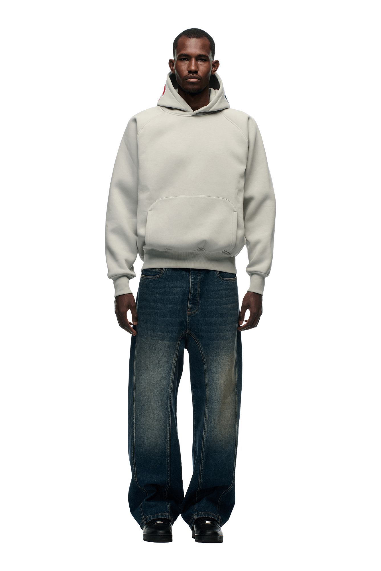 A man faces forward wearing the 6PM COLLEGE LETTER HOODIE in smoke grey and oversized dark blue faded jeans with black shoes, set against a plain white background.