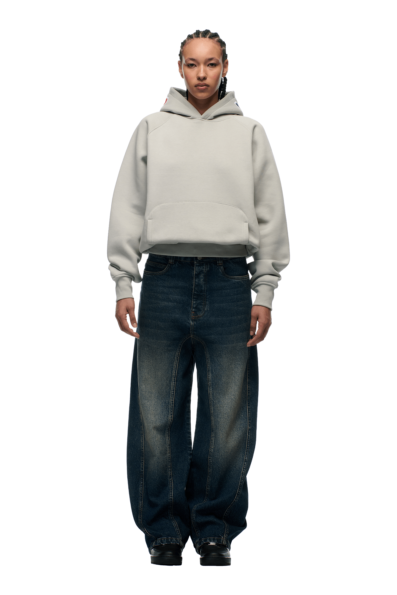 A person with braided hair wears the 6PM COLLEGE LETTER HOODIE SMOKE GREY and loose dark blue jeans, standing facing forward against a plain white background.