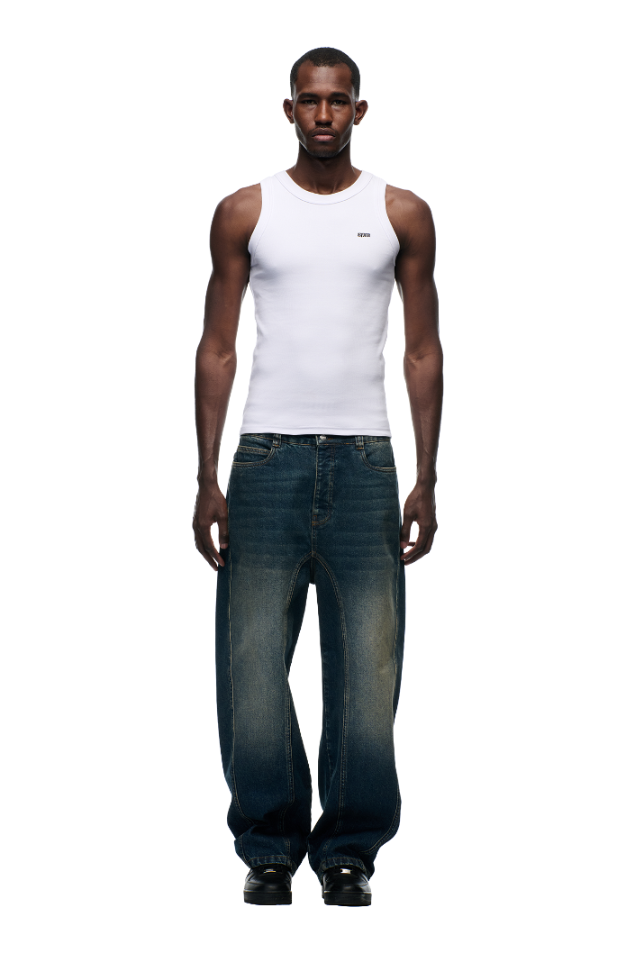 A man faces forward in a fitted white tank top and 6PM's X-TRA WIDE DENIM DARK BLUE jeans, paired with black shoes, set against a plain white background.
