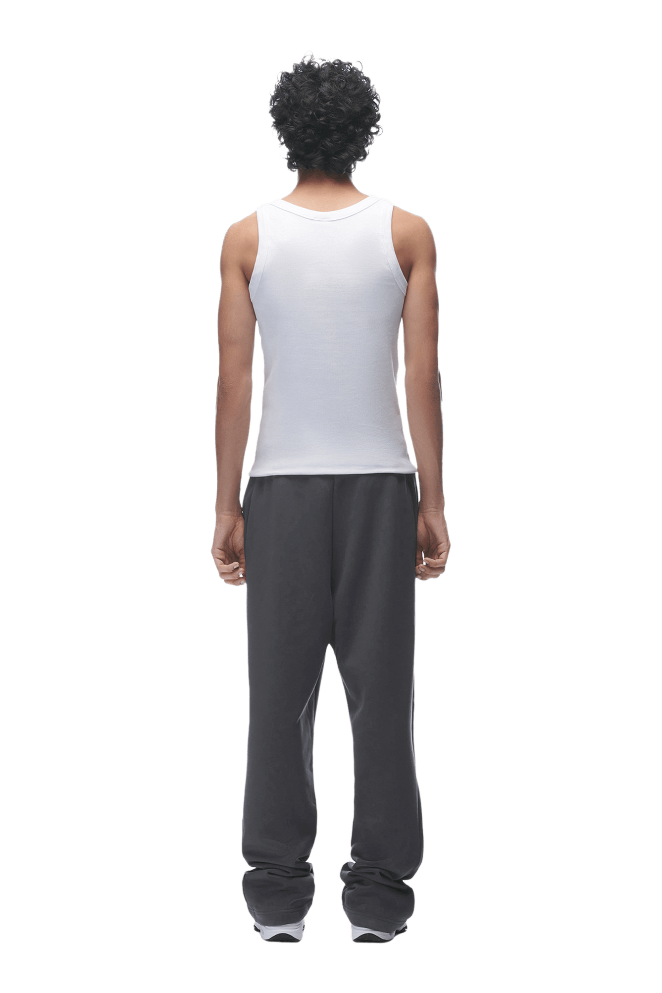 A person with curly hair, dressed in a white sleeveless shirt and 6PM’s OPEN LEG JOGGER ANTHRACITE, stands facing away from the camera against a plain background.