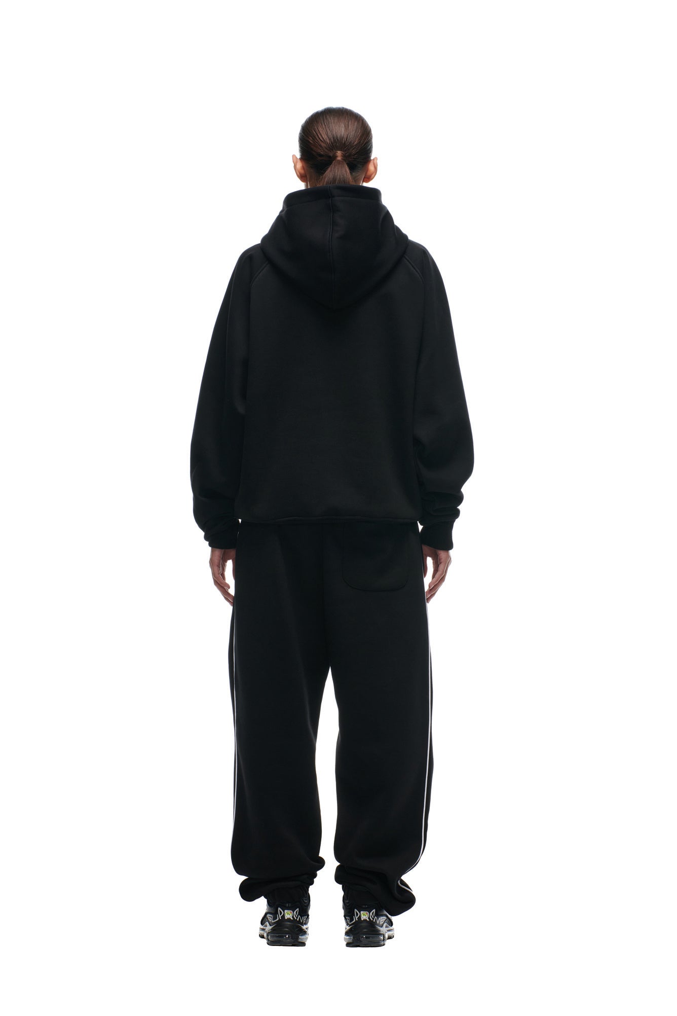 A person stands facing away from the camera, wearing the 6PM DOLPHINS SEASON HOODIE, paired with baggy black pants and black sneakers, set against a plain white background.