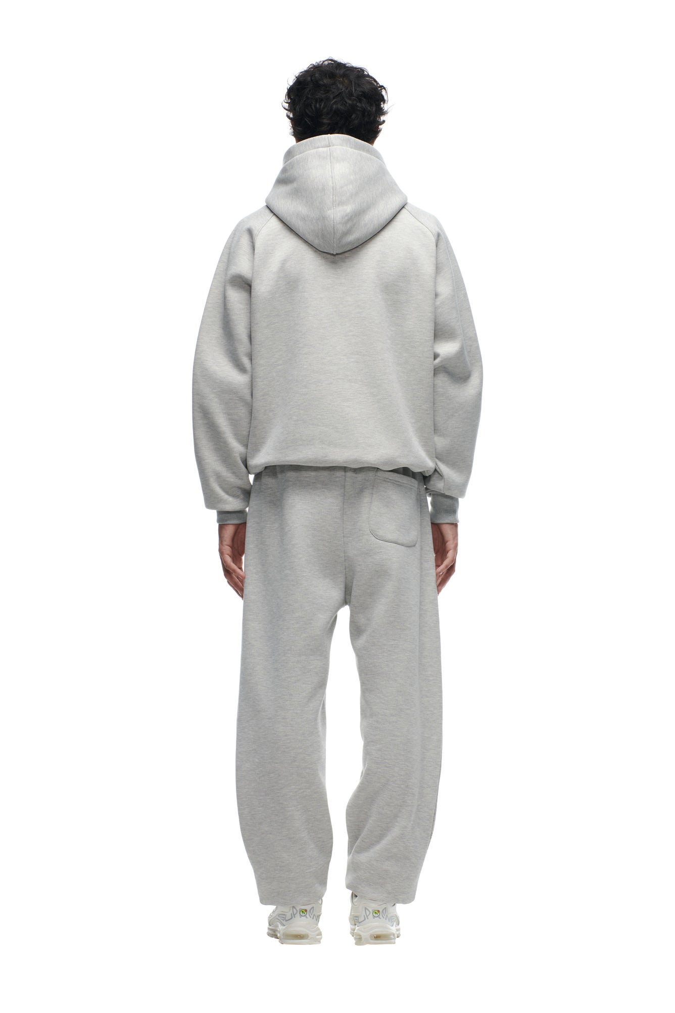 A person stands facing away, wearing the 6PM CHIEFS SEASON HOODIE in light gray with matching sweatpants and white sneakers. The outfit is loose-fitting, set against a plain white background.