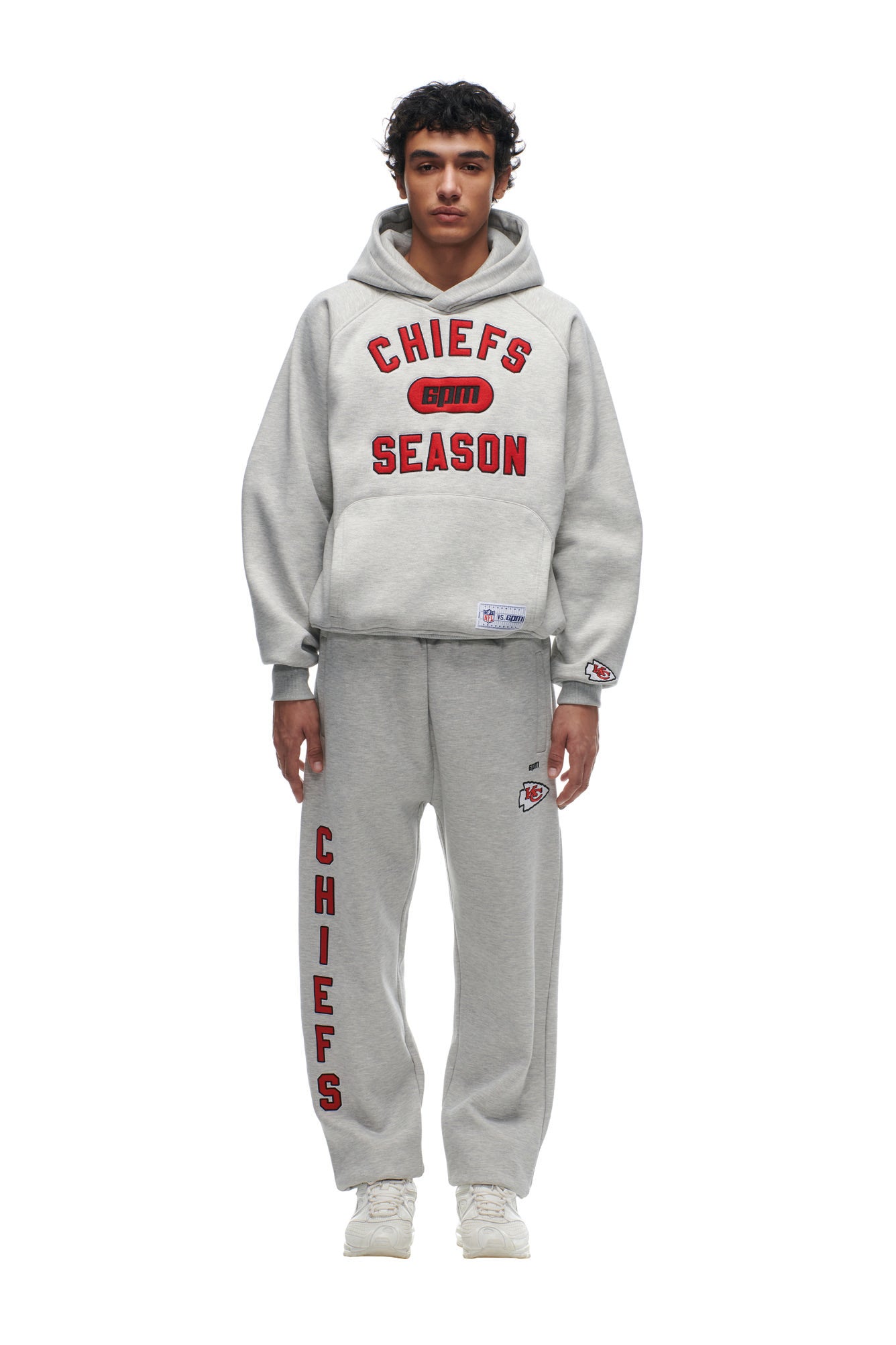 A person in a gray 6PM CHIEFS SEASON HOODIE with red "CHIEFS SEASON" text and matching sweatpants with "CHIEFS" down the leg, standing against a white background.