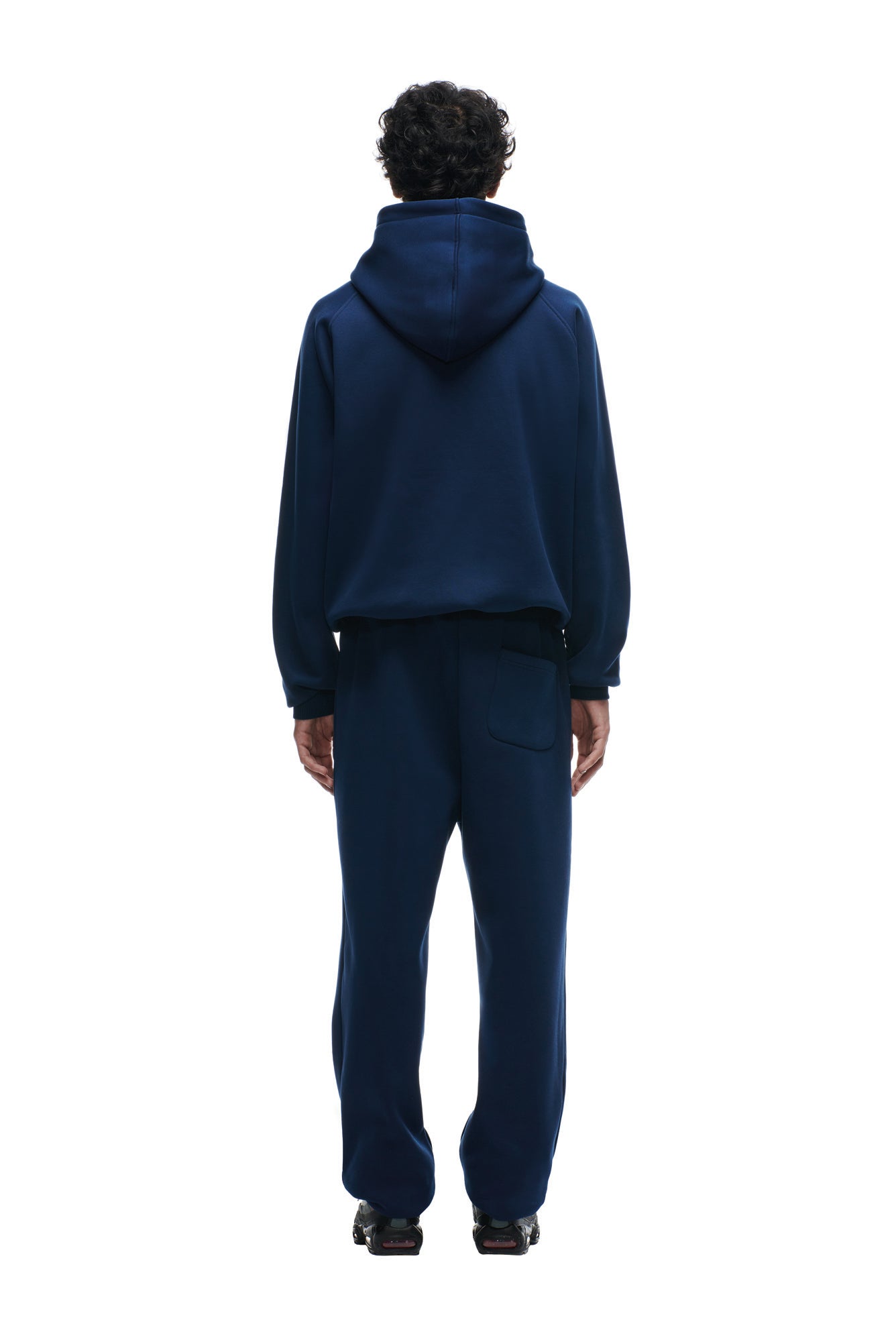 A person faces away from the camera, wearing the 6PM PATRIOTS SEASON HOODIE in navy blue with matching sweatpants, standing with relaxed hands by their sides against a plain white background.