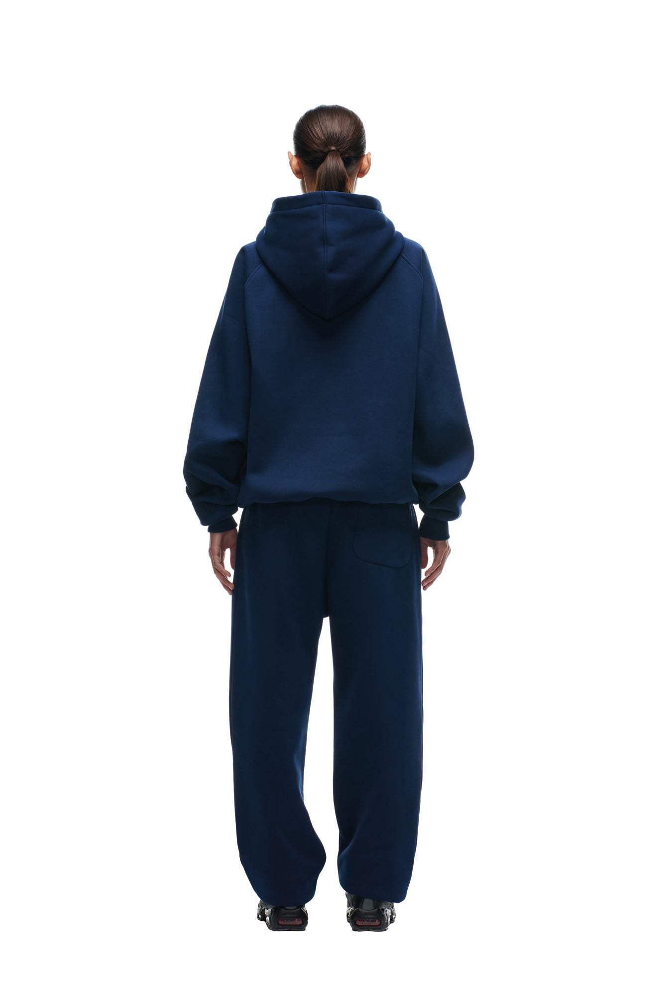 A person faces away, wearing the 6PM PATRIOTS SEASON HOODIE in dark blue with matching sweatpants, hair tied back in a low ponytail, set against a plain white background.