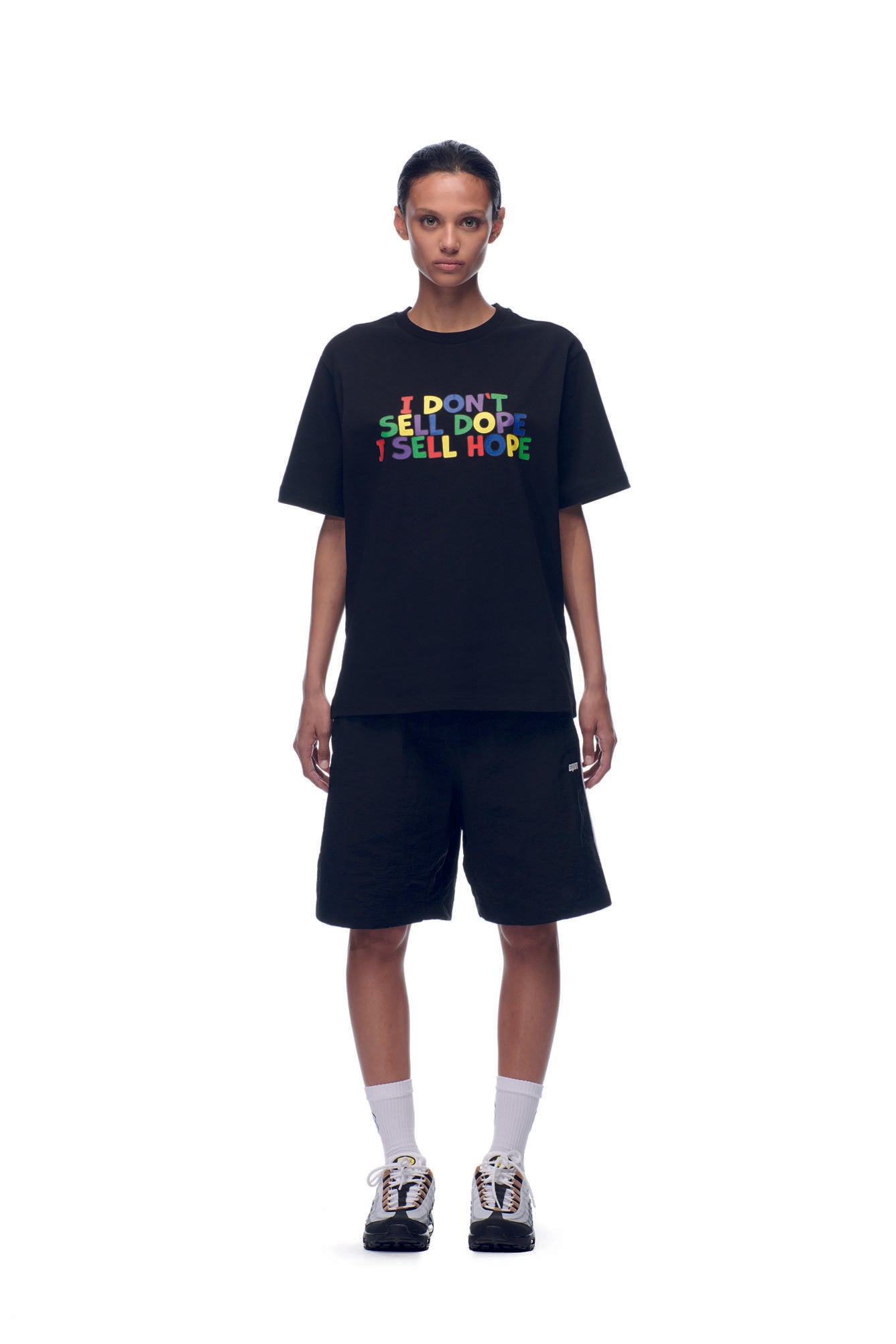 A person faces forward against a white background, wearing the 6PM SELL HOPE T-SHIRT BLACK, black shorts, white socks, and black sneakers.