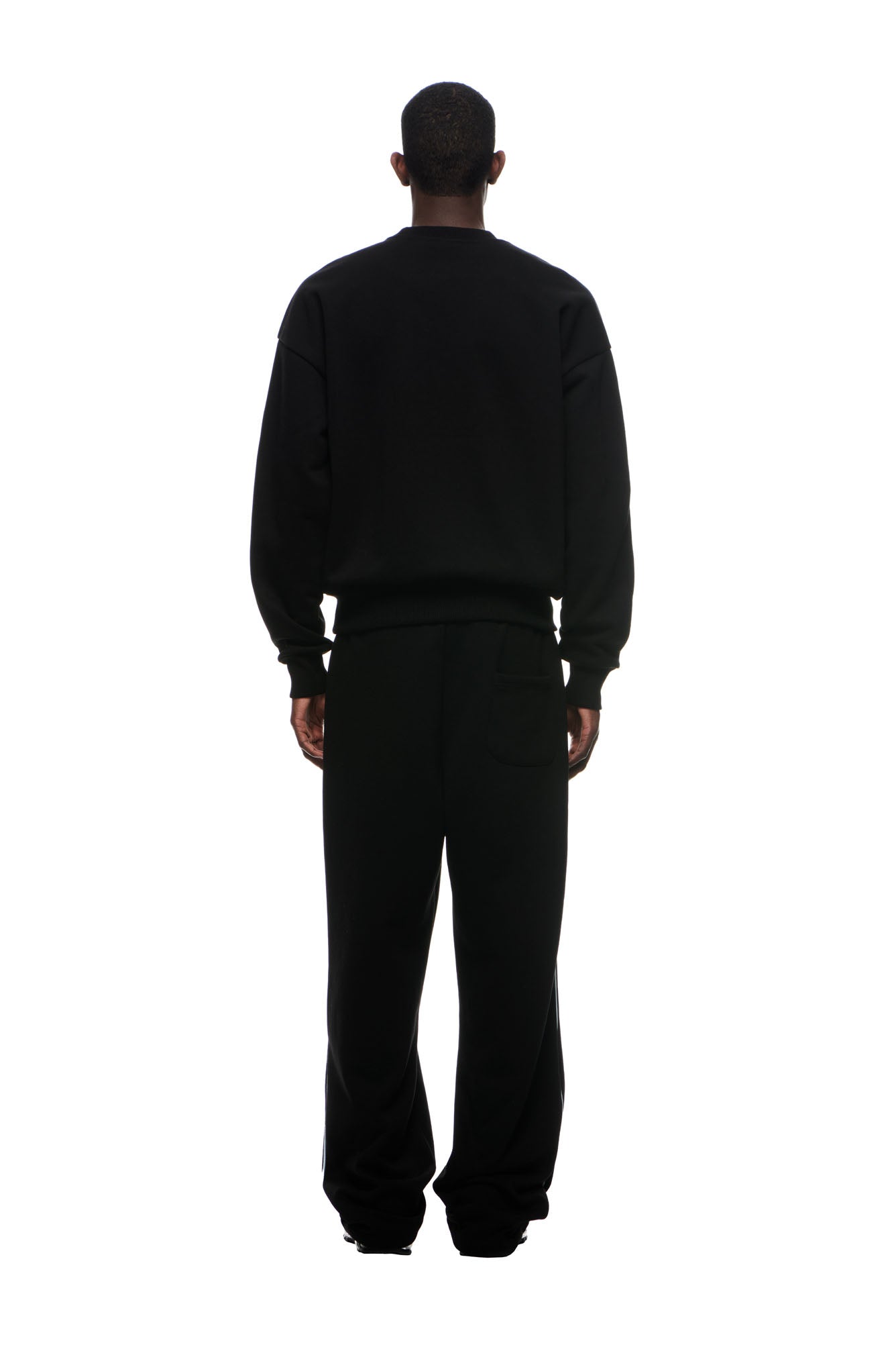 A person faces away from the camera, wearing the 6PM RECORDS CREWNECK BLACK sweatshirt and matching black pants against a white background.