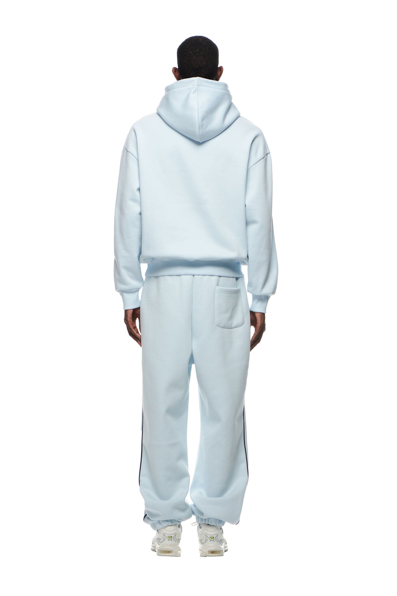 A person stands facing away, wearing the 6PM RECORDS HOODIE ICE BLUE with matching sweatpants and sneakers. The outfit is loose-fitting and casual, set against a plain white background.