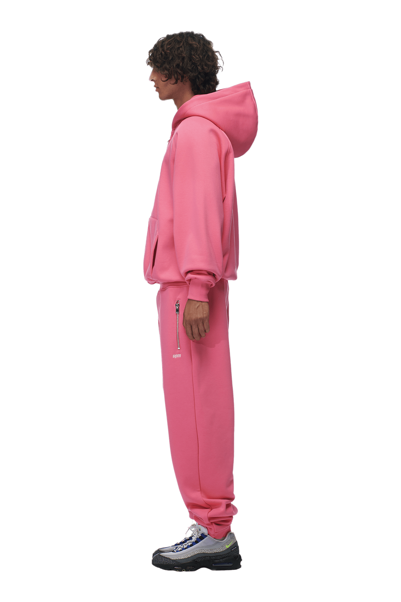 A person stands in profile against a transparent background wearing the 6PM ZIP HOODIE HOT PINK set paired with black and white sneakers, showcasing a clean finish.