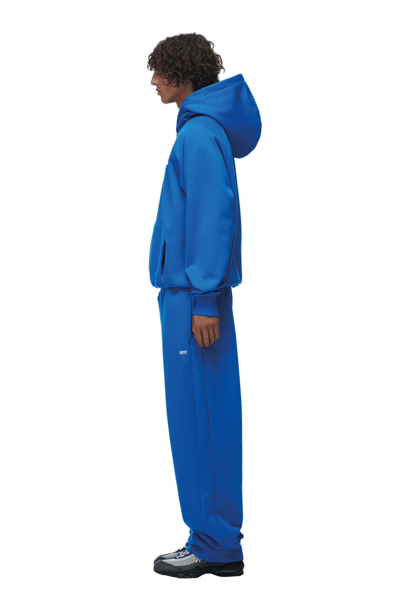 A person in profile models the 6PM HOODIE PRINCESS BLUE with Raglan sleeves and kangaroo pocket, paired with matching sweatpants and black sneakers against a plain background—ideal for daily wear.