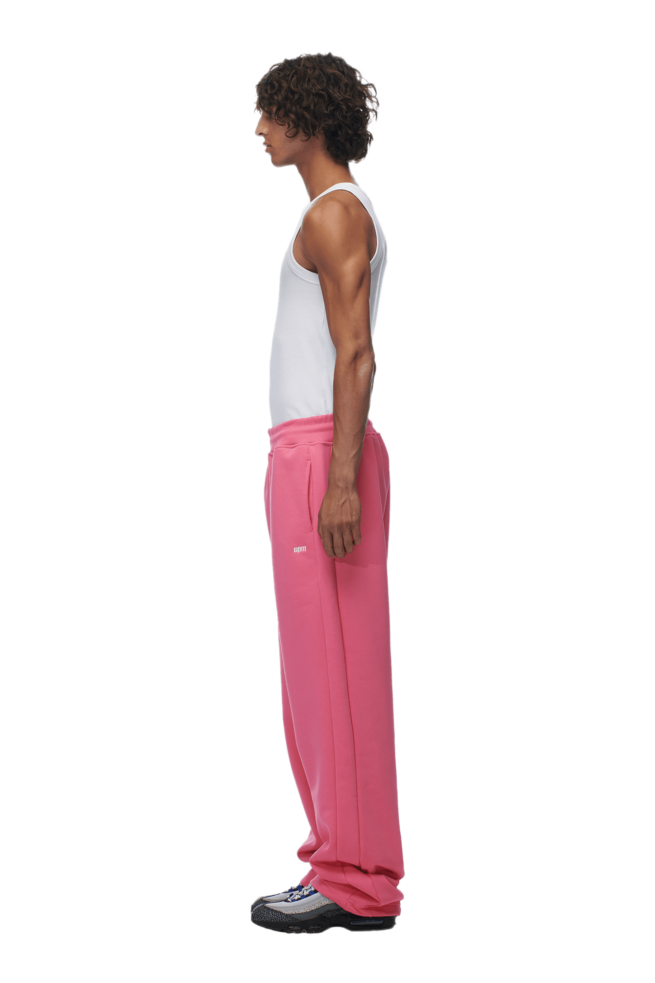 A man in profile wears a white tank top, 6PM OPEN LEG JOGGER HOT PINK sweatpants with ideal stacking length, and black sneakers, all shown against a transparent background.