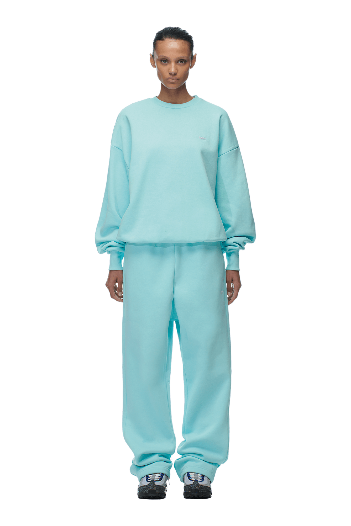 A person stands facing forward wearing the 6PM CREWNECK TURQUOISE sweatshirt and matching sweatpants, paired with black and gray sneakers. The background is transparent.