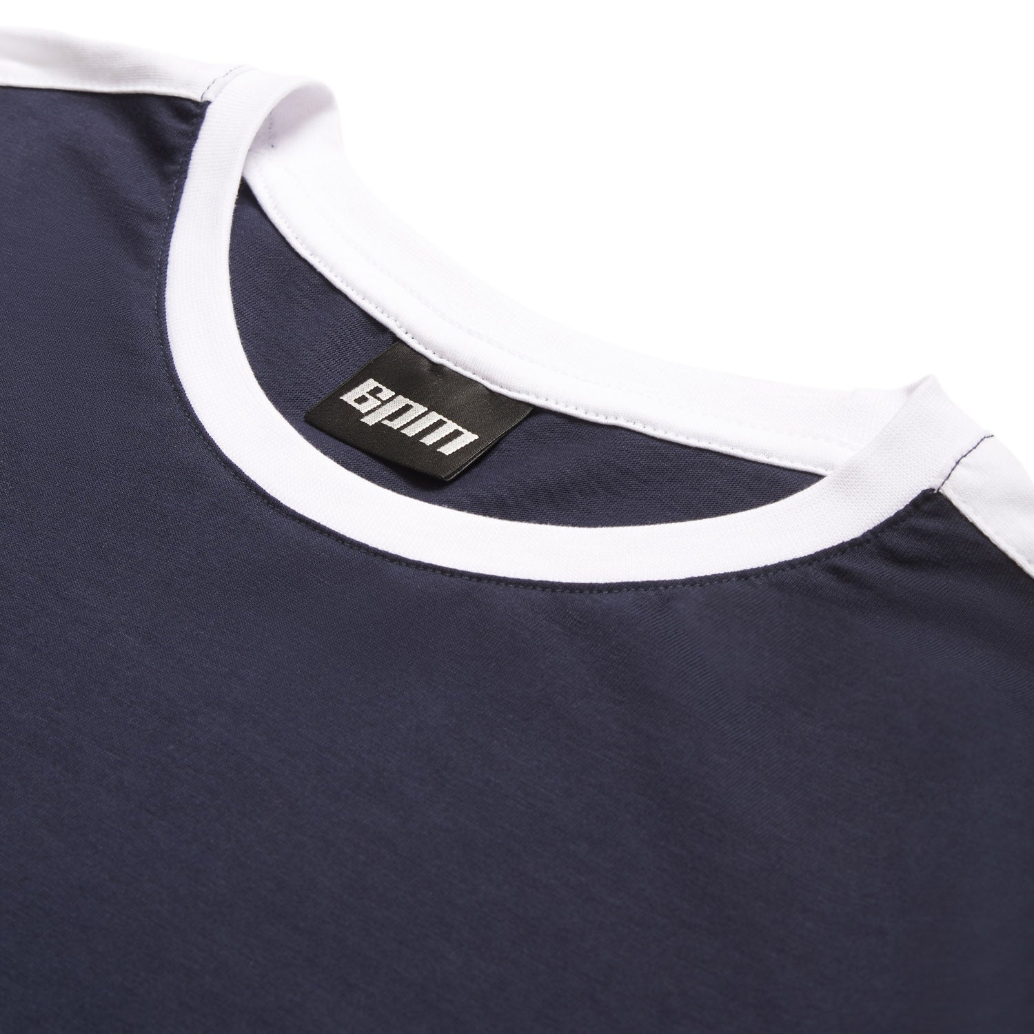 A close-up of the 6PM GRAFFITI RINGER LS MIDNIGHT BLUE shows its navy fabric, white collar, and a black label with white text sewn inside the neckline, laid flat on a white background.