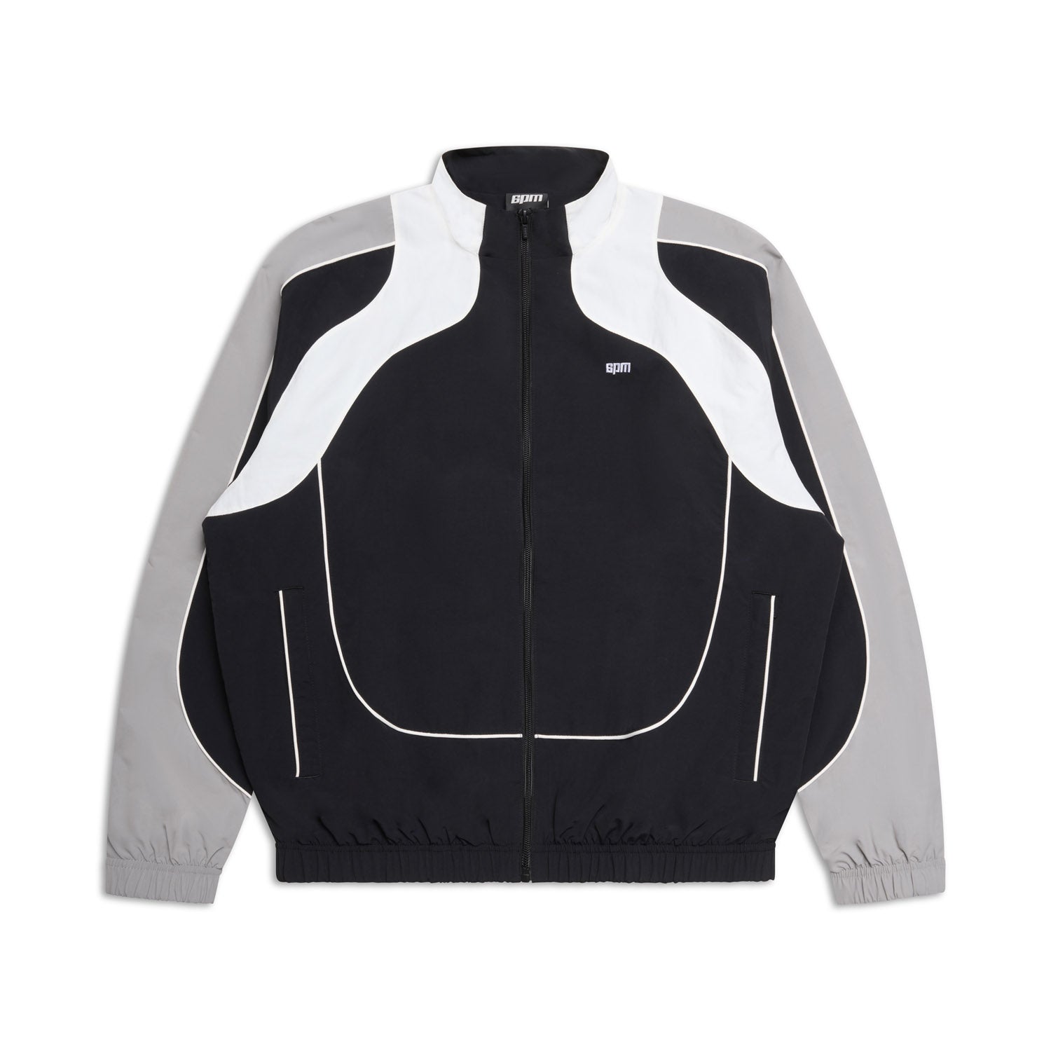 The 6PM EVERYDAY TRACK JACKET BLACK features light grey sleeves, white curved chest and shoulder accents, a high collar, elastic cuffs, zip-up front, and a small white logo on the left chest.