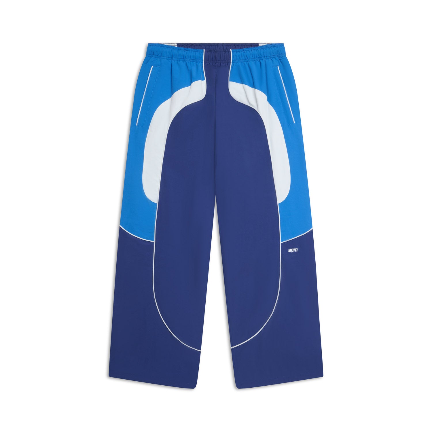 The 6PM EVERYDAY TRACK PANTS SHADOW BLUE feature blue and white wide-leg panels, white piping, an elastic waistband, and side pockets, shown on a white background.