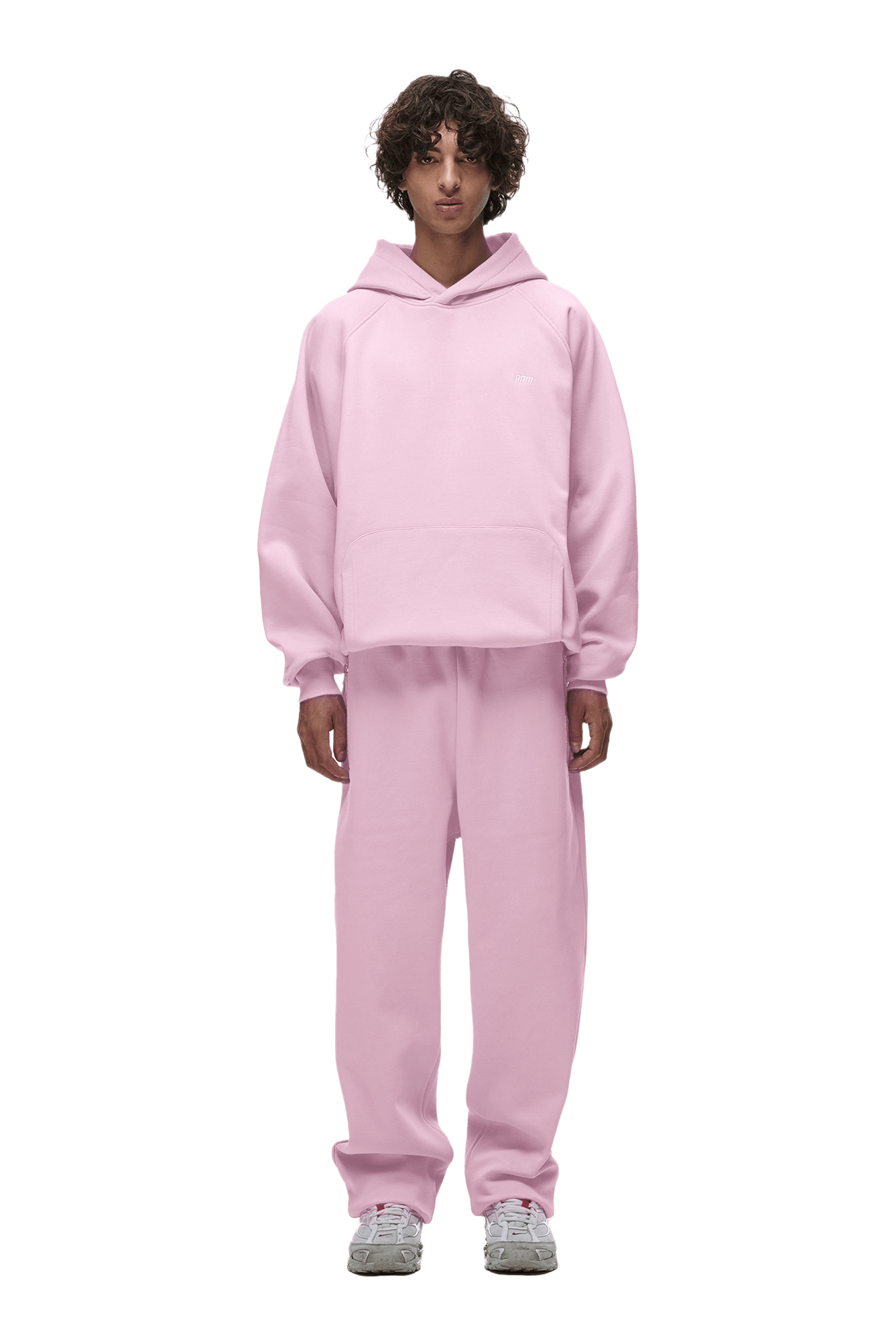 A person stands facing forward against a white background, wearing the 6PM HOODIE BABY PINK with matching sweatpants and gray sneakers.