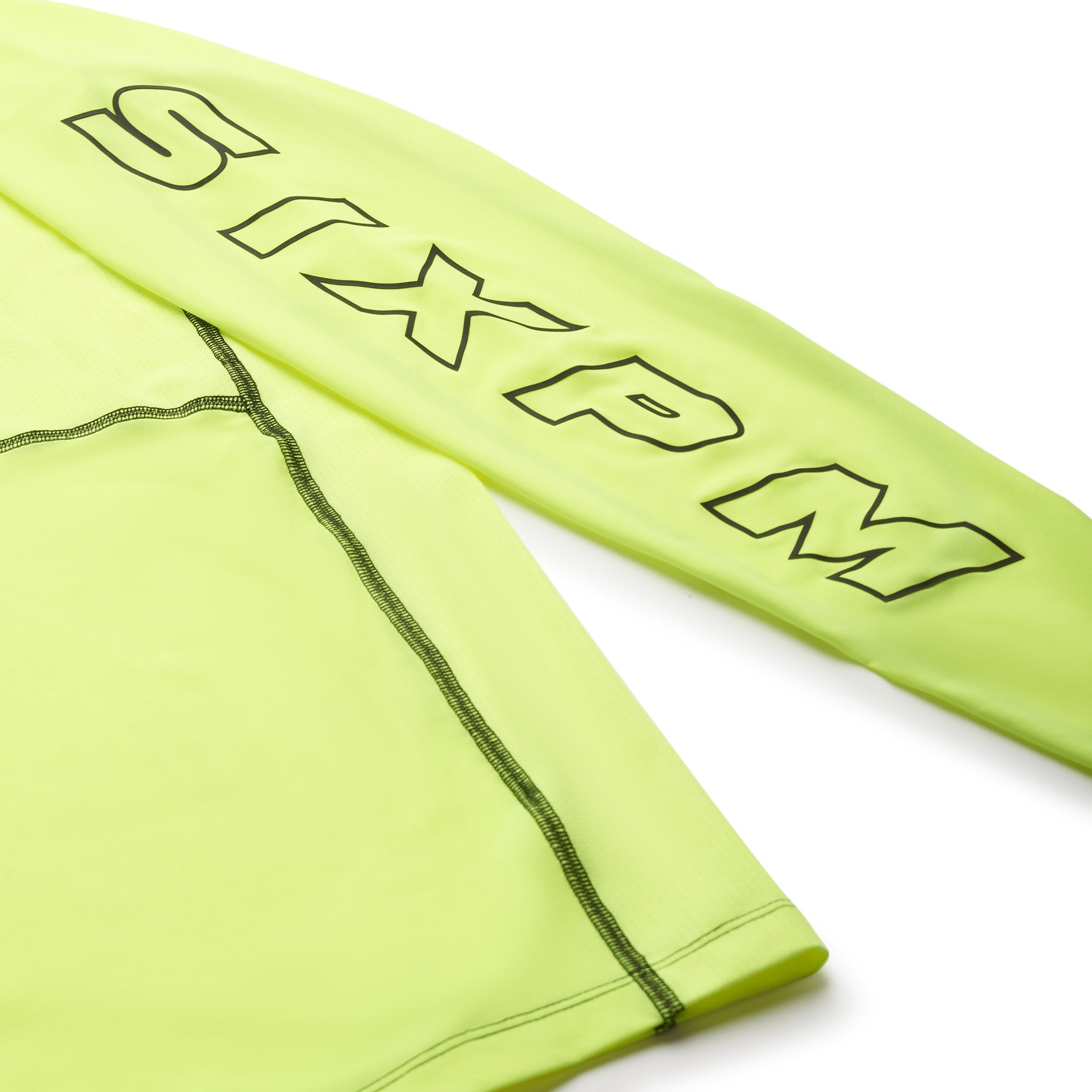 A close-up of the 6PM SPORTS LONGSLEEVE NEON YELLOW by 6PM, featuring black stitching and bold SIXPM lettering along the sleeve.
