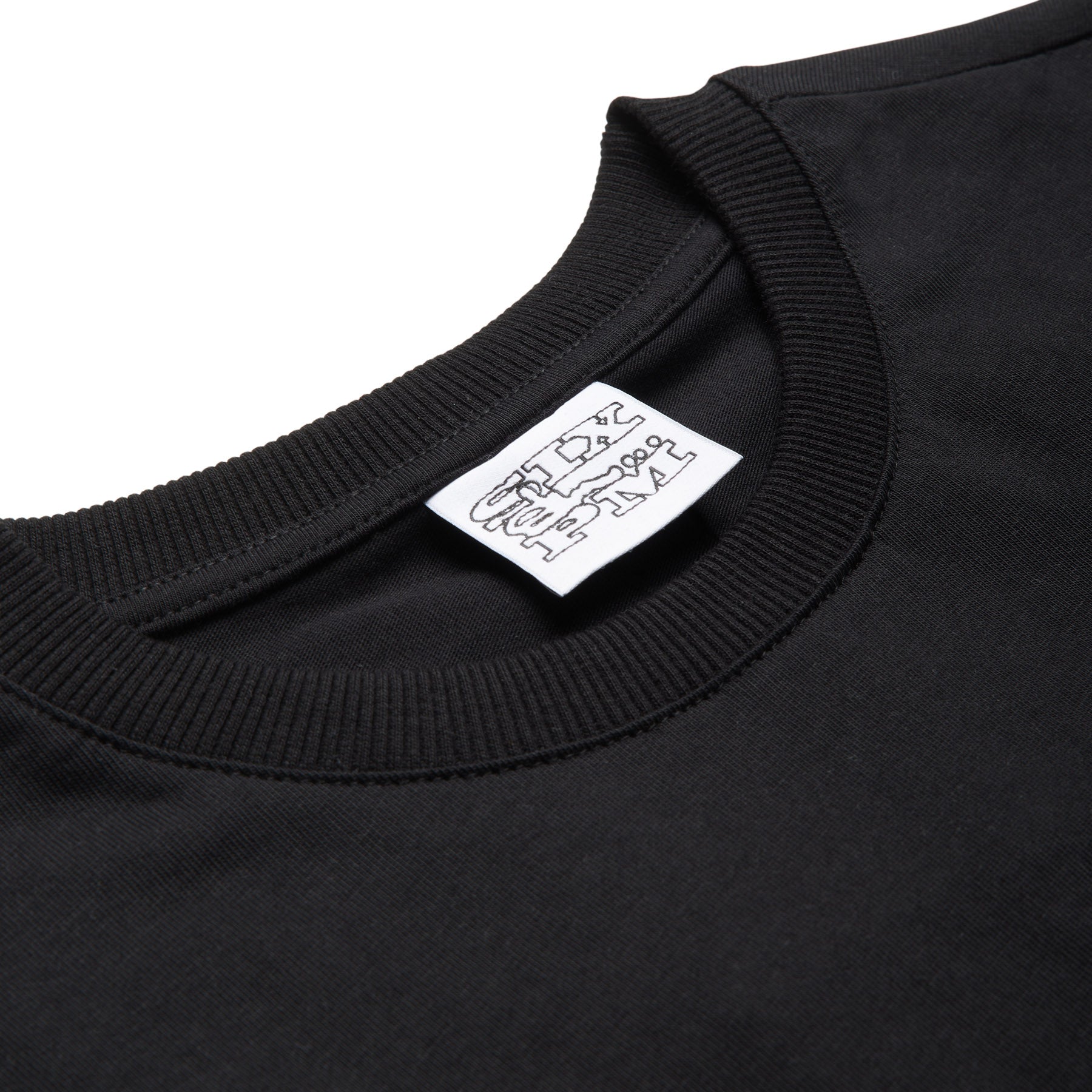A close-up of the 6PM SLAWN SIGNATURE TEE BLACK shows its smooth black fabric, visible neckline stitching, and a white tag with black doodle-style text by the collar.