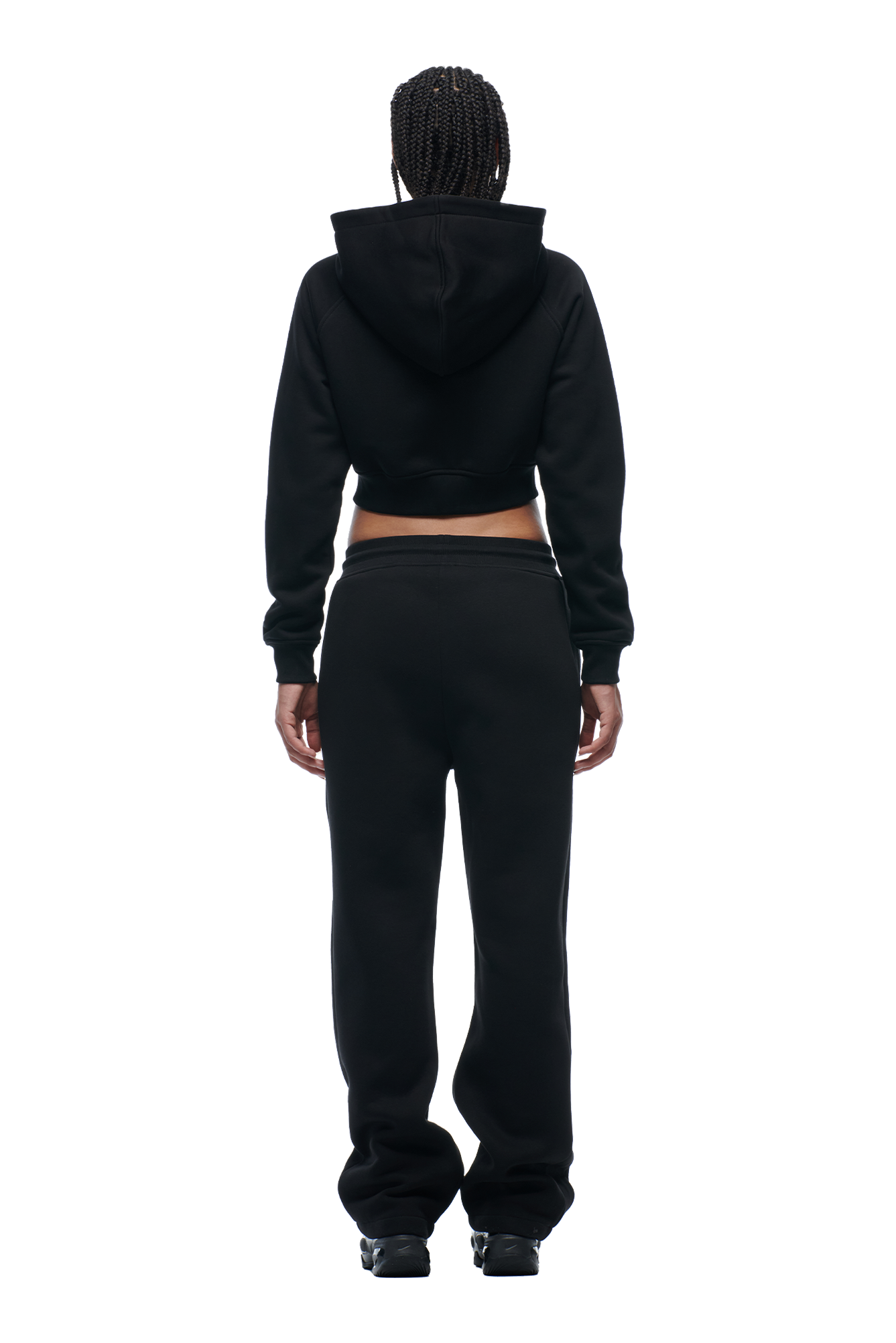 A person with braided hair is seen from the back, wearing the 6PM WMNS CROPPED ZIP HOODIE BLACK and matching black sweatpants.