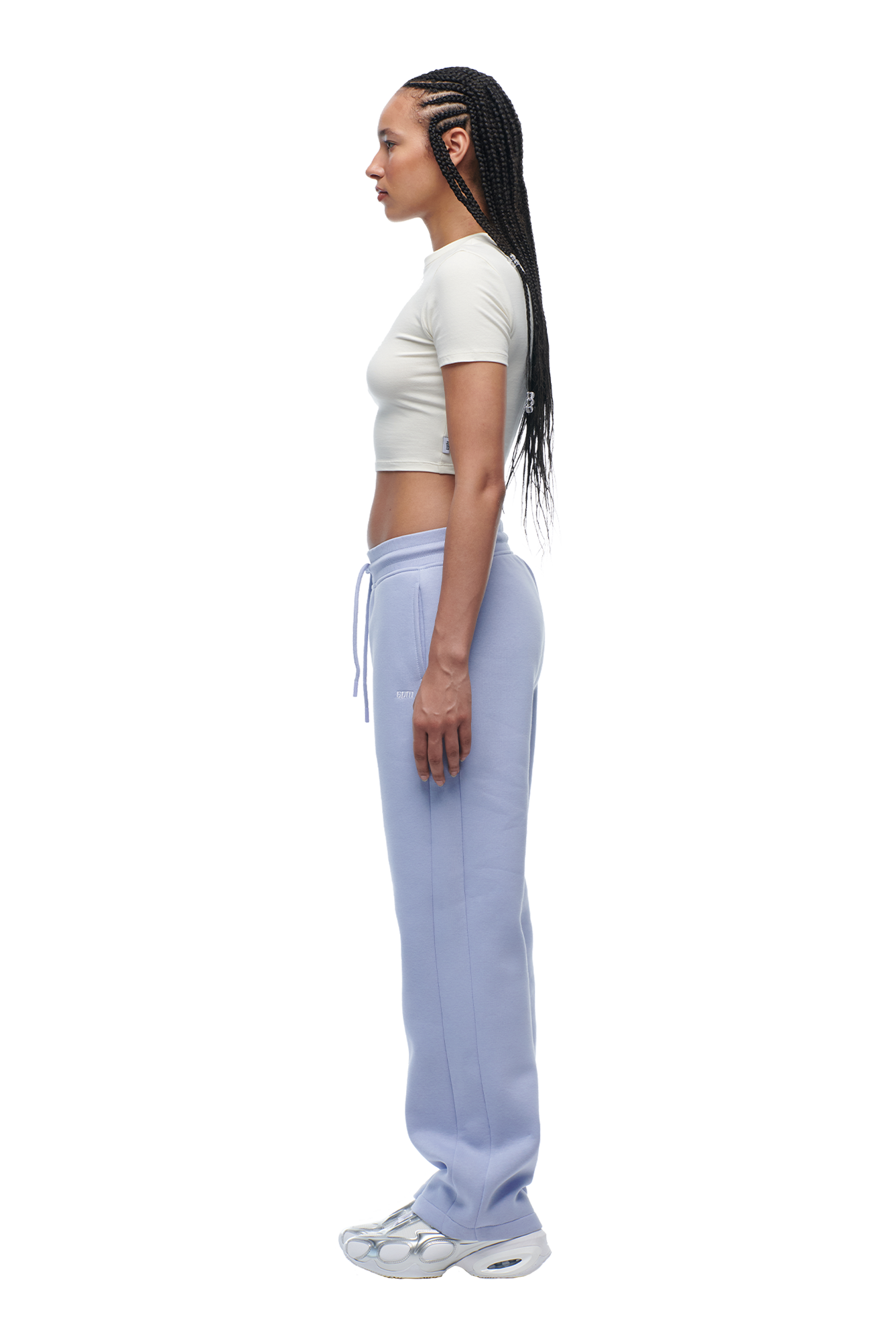 A woman wearing a 6PM WMNS Cropped T-Shirt Off-White and purple sweatpants.