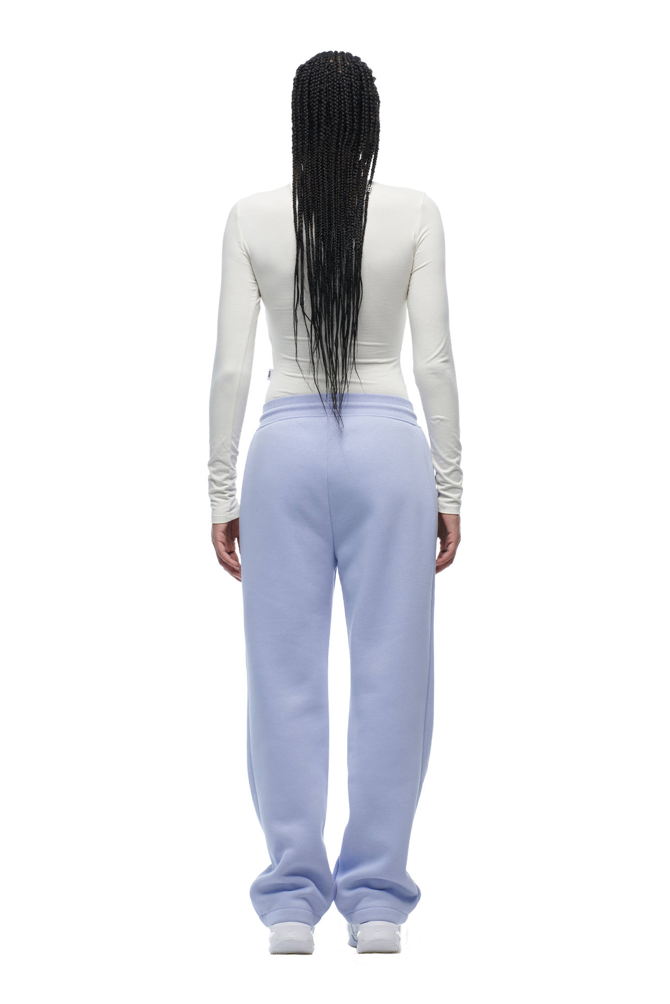 A person with long, braided hair stands facing away, wearing the 6PM WMNS LONGSLEEVE OFF-WHITE top and loose, light blue sweatpants.
