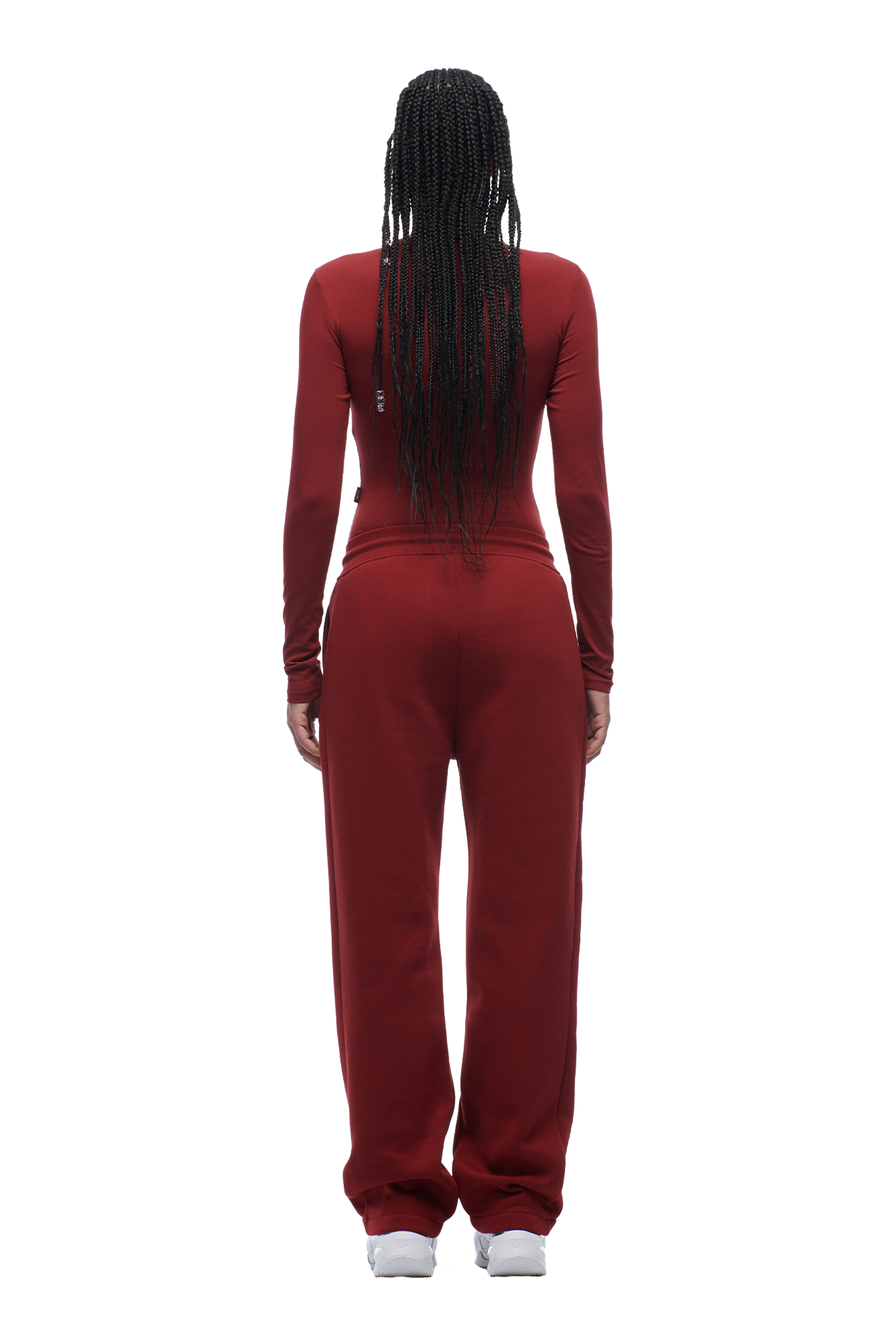 A person with long braided hair faces away, wearing the 6PM WMNS LONGSLEEVE WINE RED top, matching maroon sweatpants, and white sneakers against a white background.