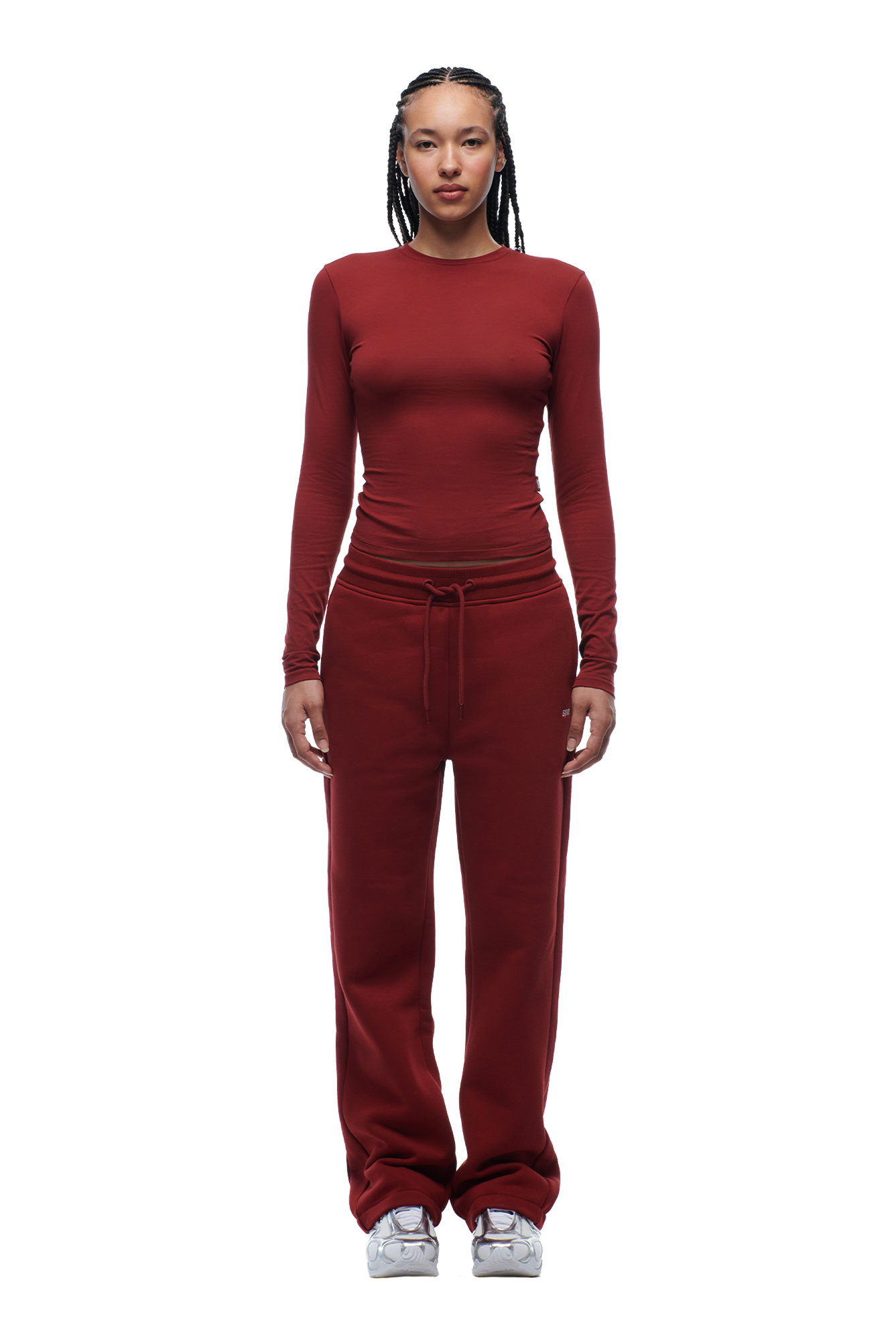 A person with braided hair faces forward, wearing the 6PM WMNS LONGSLEEVE WINE RED top and matching bottoms with white sneakers against a white background.