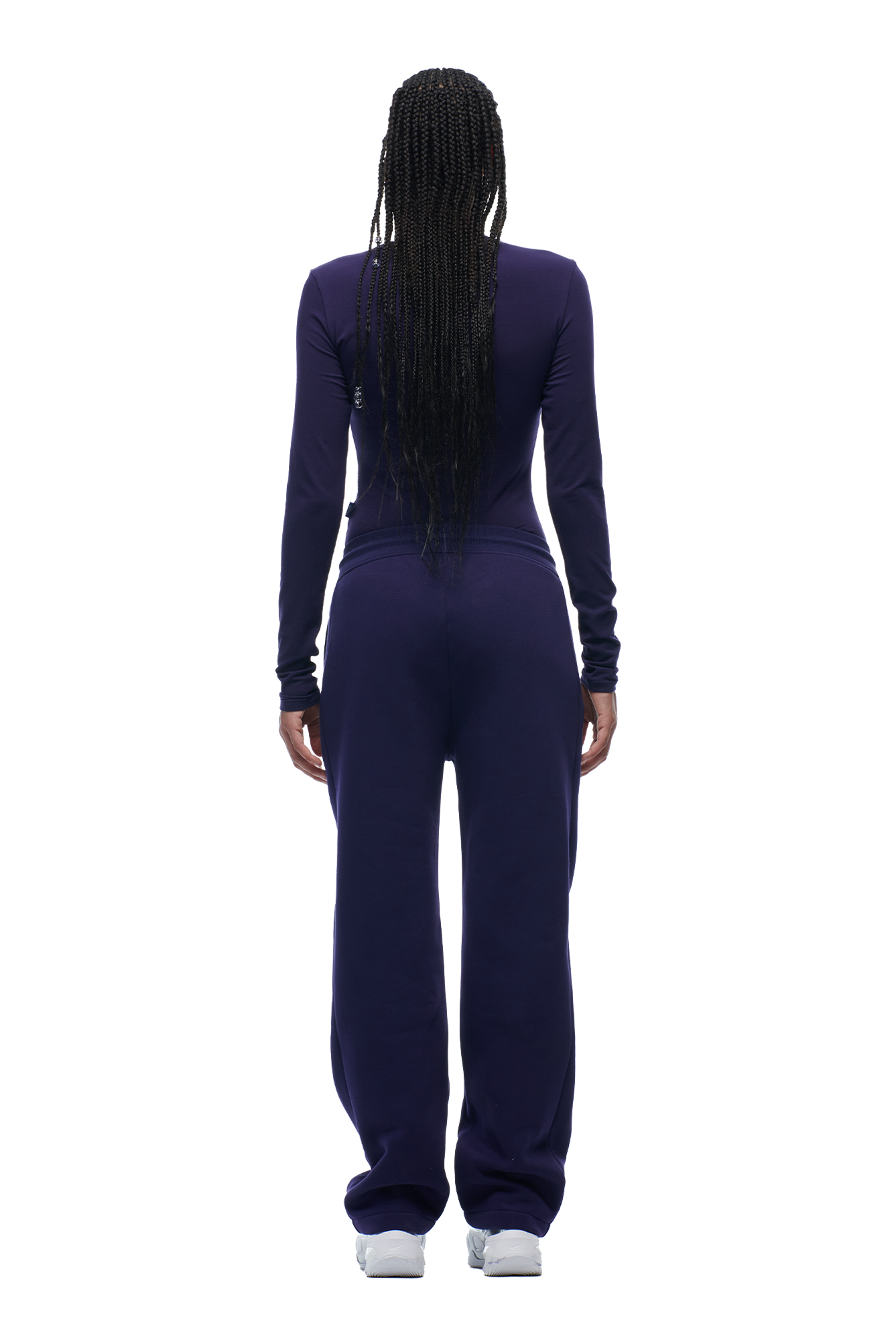 A person with long braided hair models the 6PM WMNS LONGSLEEVE ORBIT BLUE top and matching pants, standing with their back to the camera against a white background.