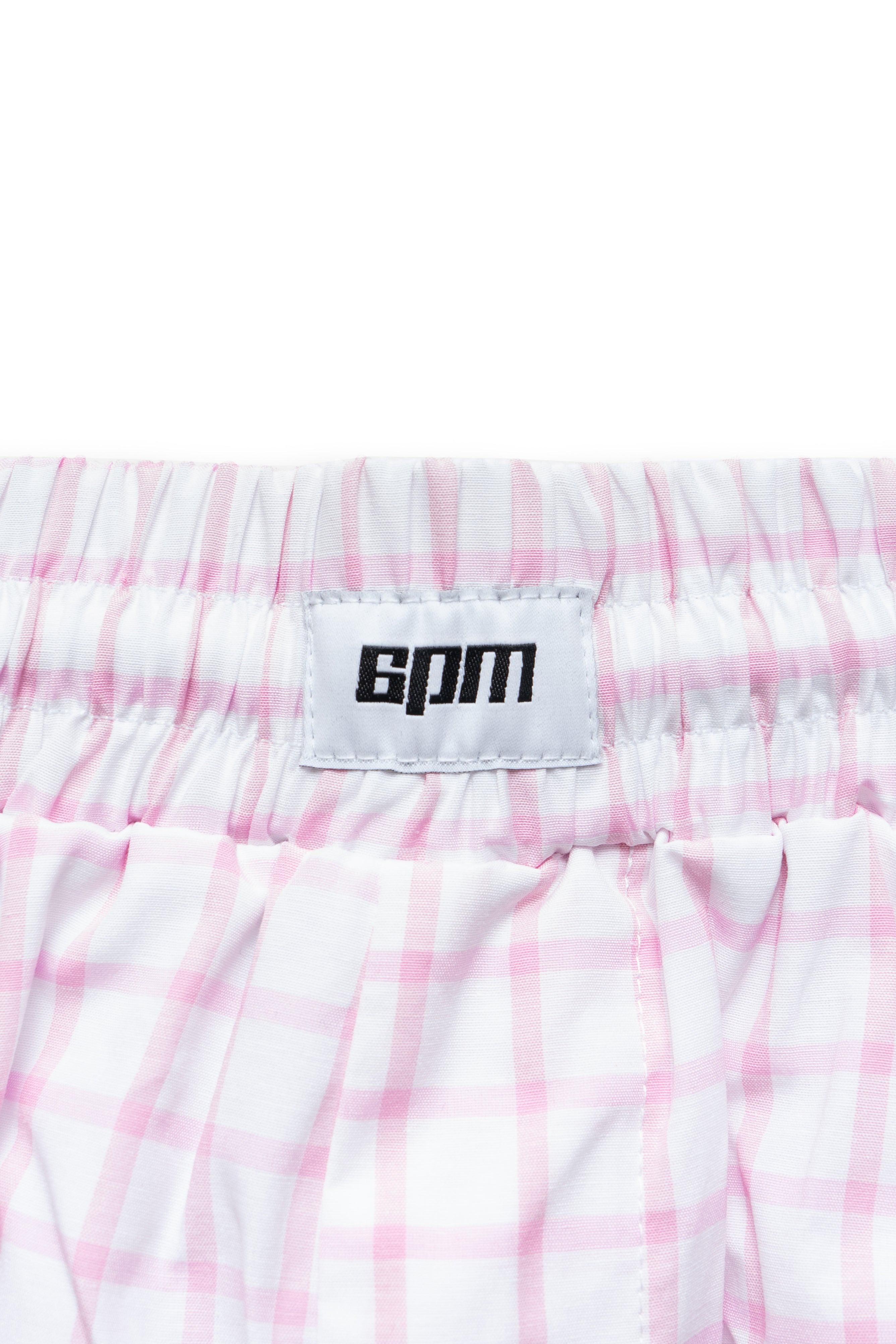 Close-up of the waistband on 6PM BOXERSHORTS SHORTS WHITE/PINK, featuring a pink plaid pattern and a white label with “bpm” in bold black letters sewn onto the band.