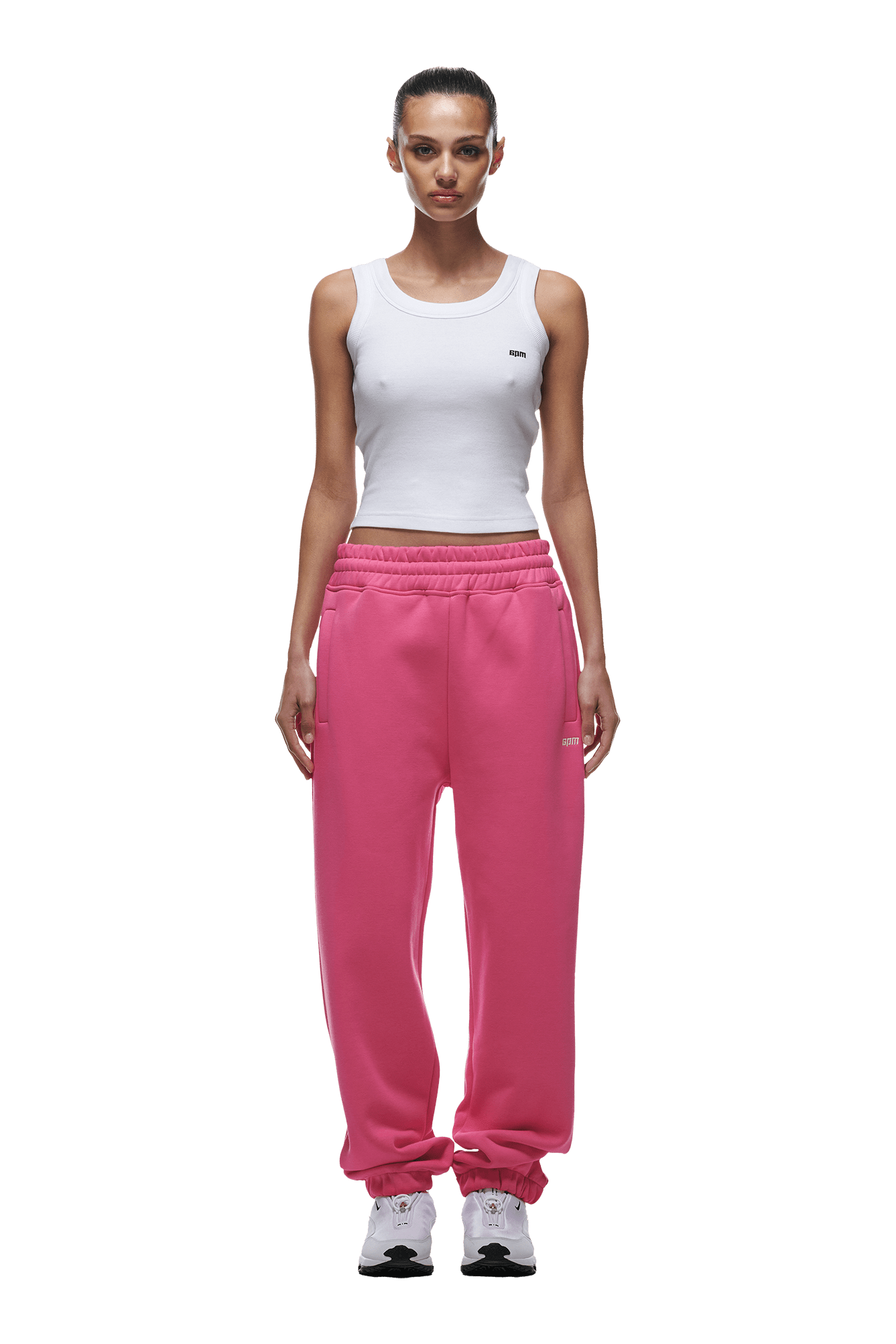 A woman faces forward in a white tank top and 6PM CUFF JOGGER HOT PINK sweatpants with a classic fit and cuffed legs, paired with white sneakers. Her hair is pulled back, expression neutral. Background is transparent.