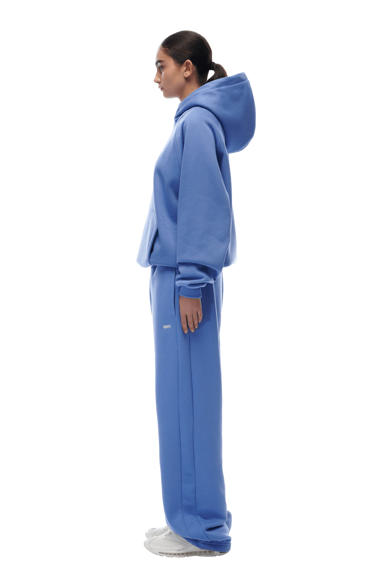 A person in profile wears the 6PM HOODIE PERSIAN BLUE with matching sweatpants and white sneakers against a transparent background—perfect for everyday style.