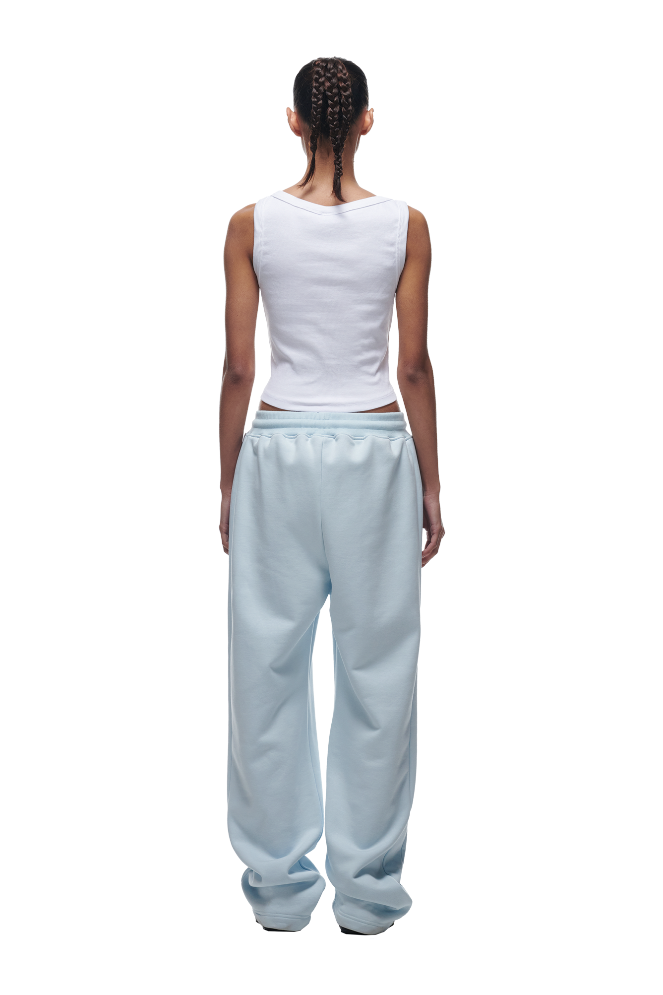 A person with braided hair, seen from behind, wears a white sleeveless top and 6PMs OPEN LEG JOGGER ICE BLUE sweatpants against a white background.