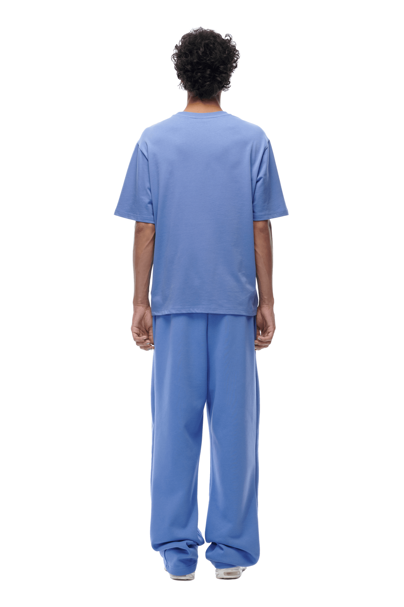 A person faces away, wearing the 6PM T-SHIRT PERSIAN BLUE with matching wide-leg pants and white shoes, shown against a transparent background.