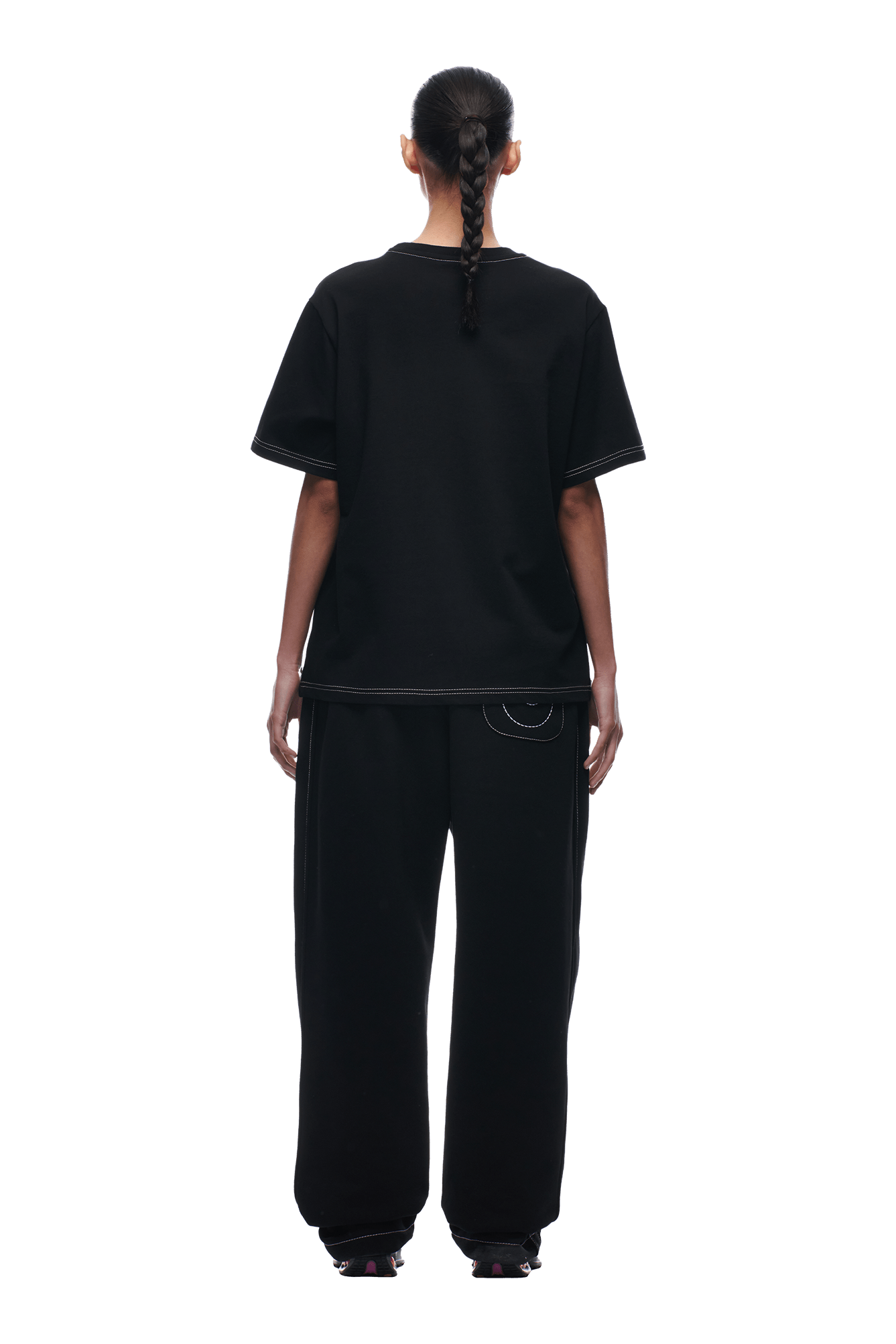A person with a single braid is seen from behind, wearing the 6PM BUDDHA T-SHIRT BLACK and black wide-legged pants with white stitching, standing against a plain white background.