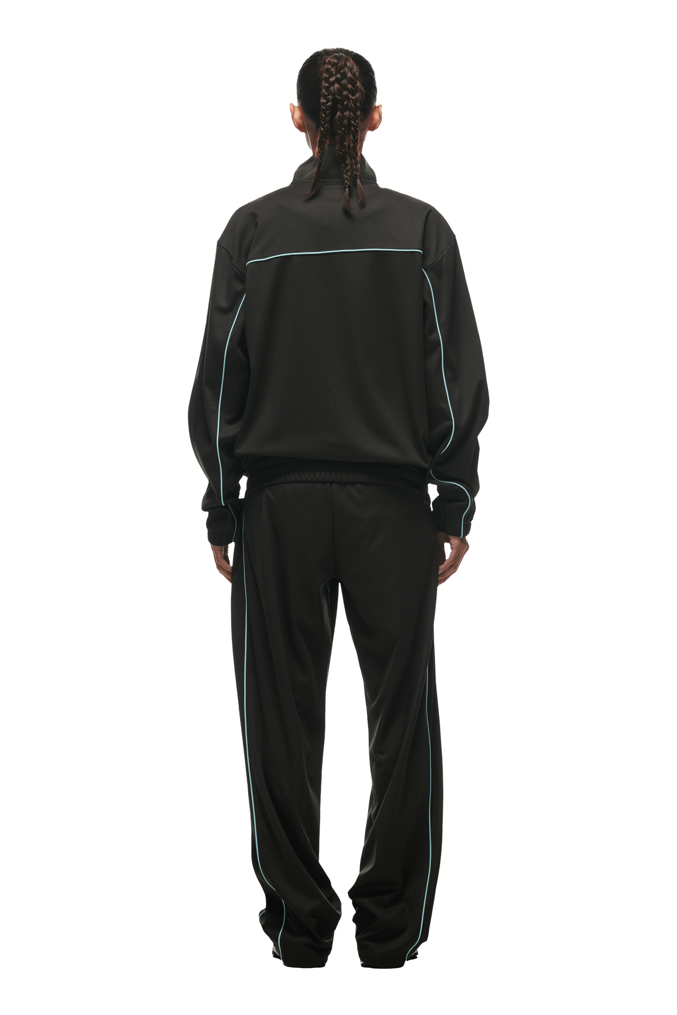 Person with braided hair wears the 6PM 6PM+ TRAINER JACKET ANTHRACITE, featuring white piping and zipped pockets, standing back to the camera against a green background—an urban streetwear look.