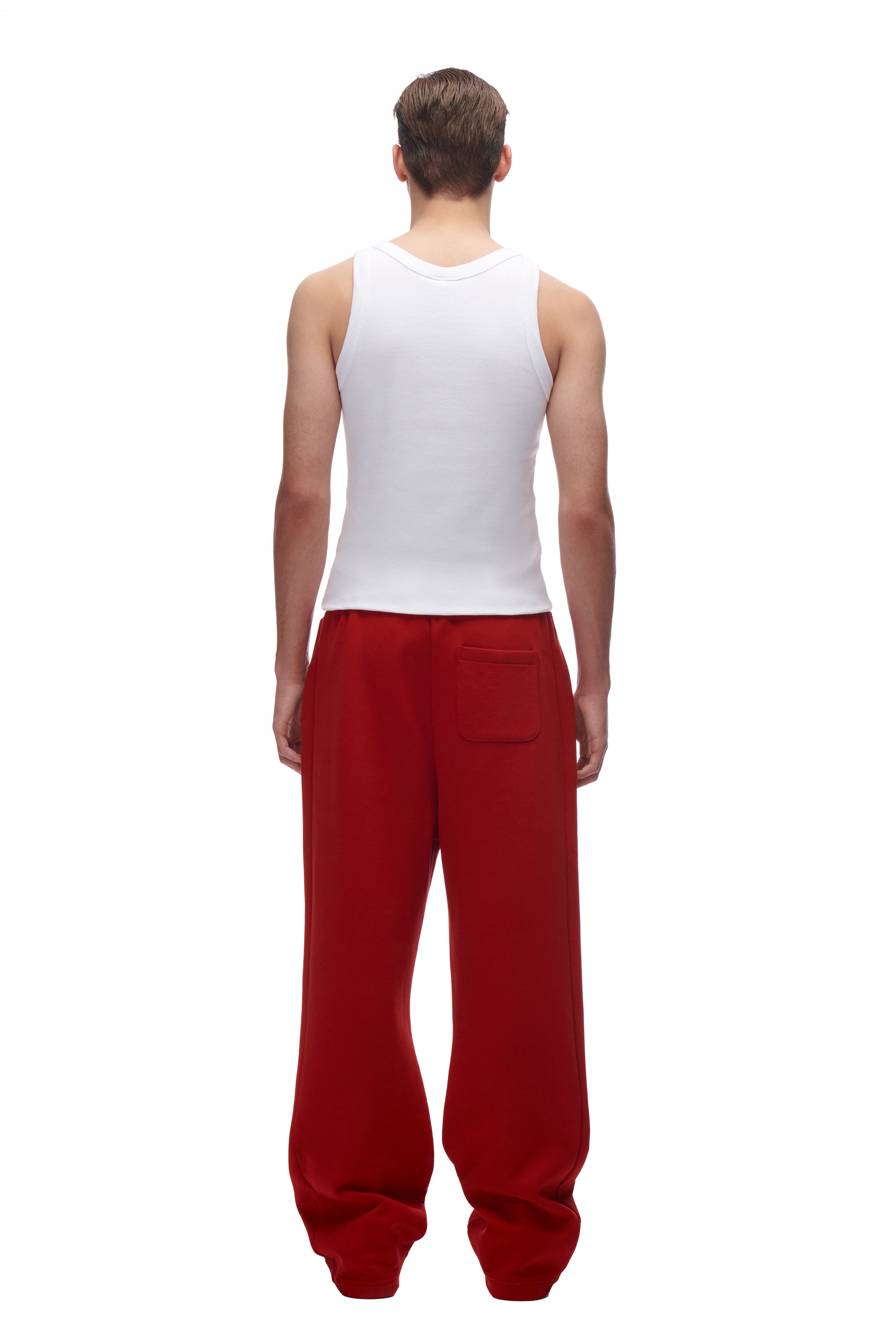 A person stands facing away in a white sleeveless tank top and 6PM LH SWEATPANT RED, which features a back pocket. The background is plain white.
