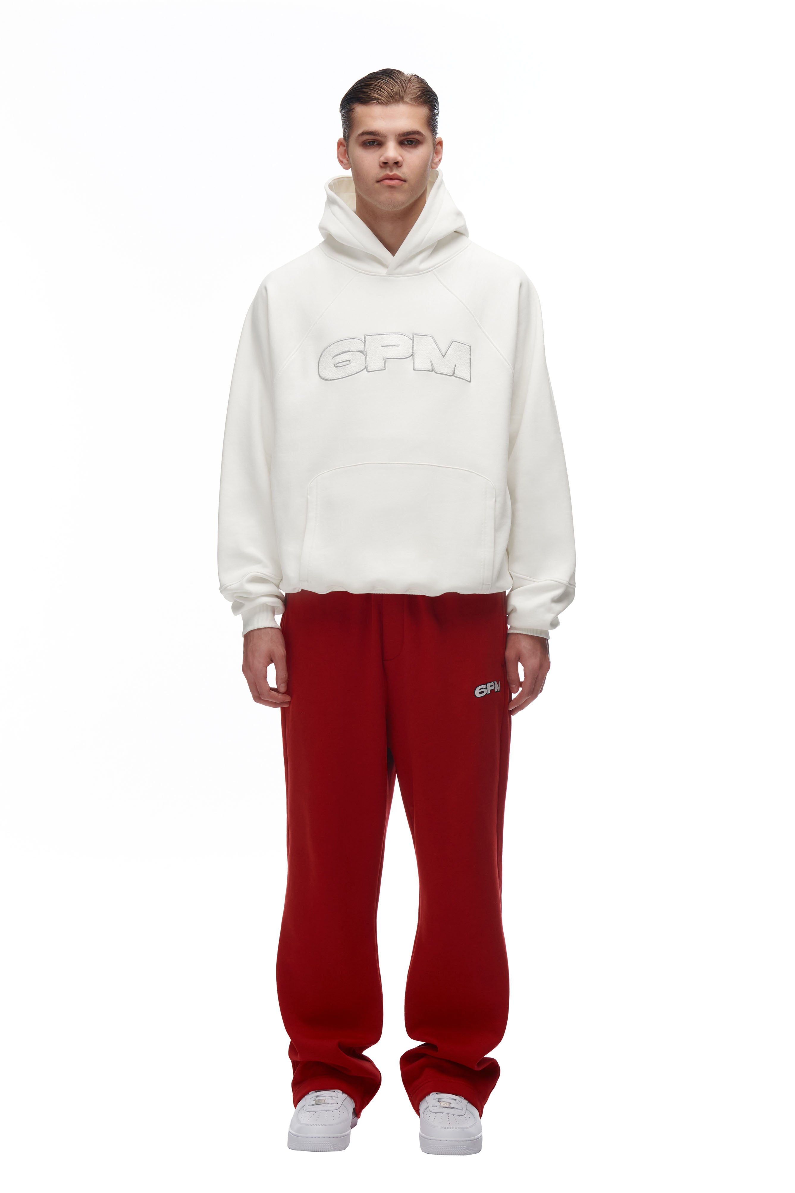 A man wearing a 6PM LH HOODIE OFFWHITE and red pants.