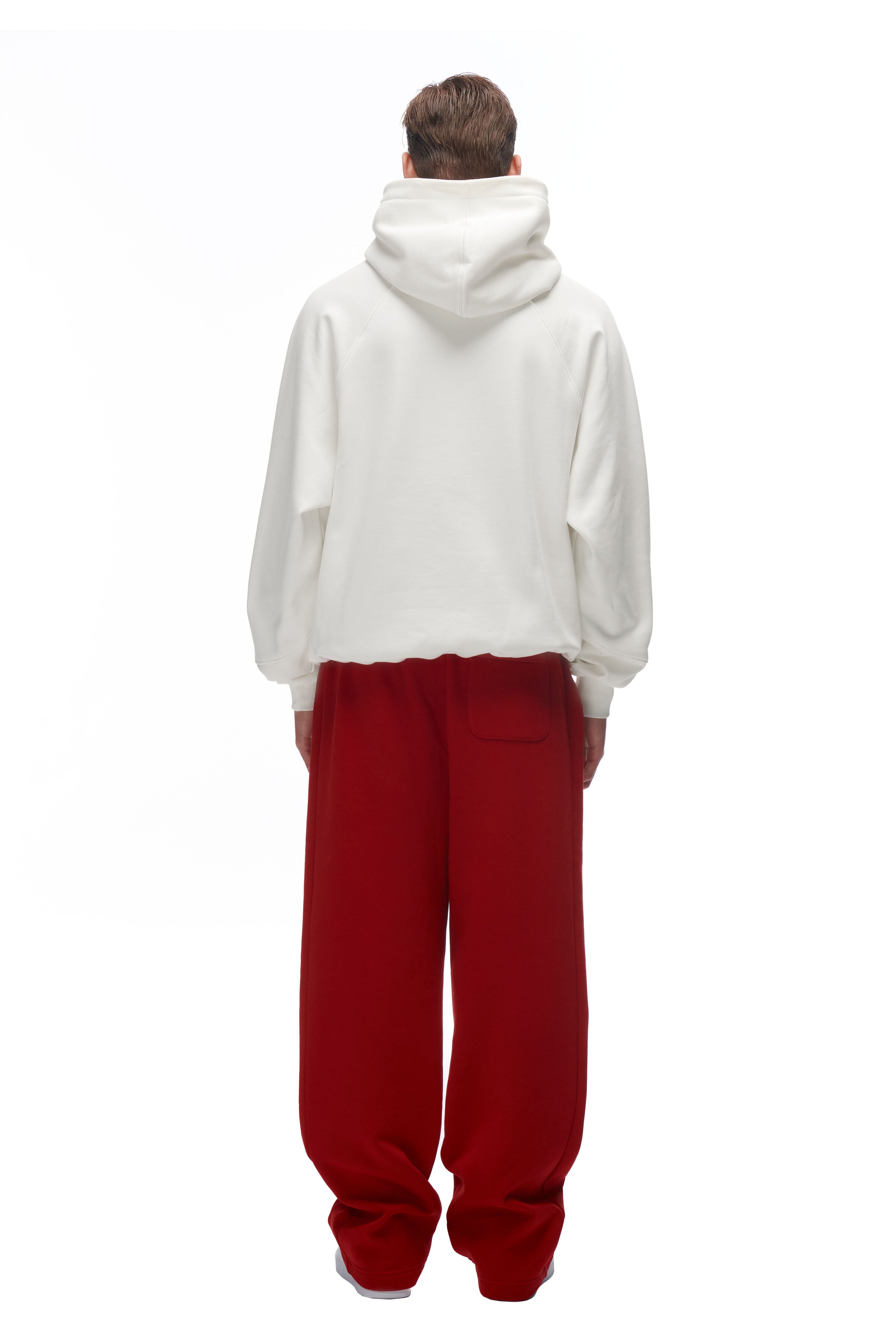 A person faces away from the camera, wearing the 6PM LH HOODIE OFFWHITE and loose red pants against a plain white background.