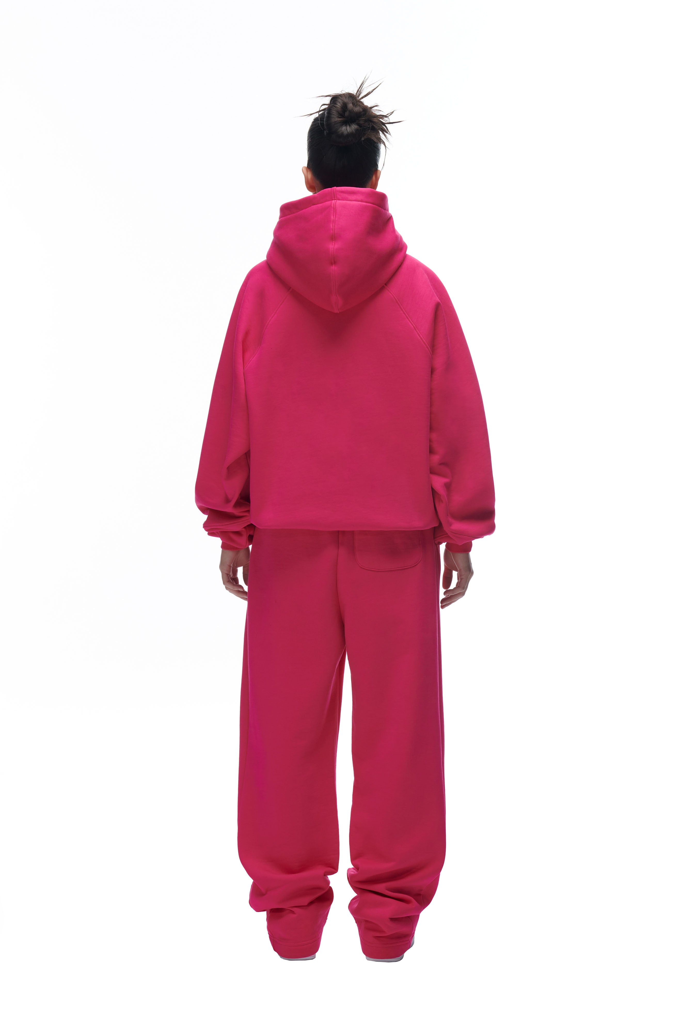 A person with their hair in a messy bun faces away from the camera, wearing the 6PM LH HOODIE PINK against a white background.