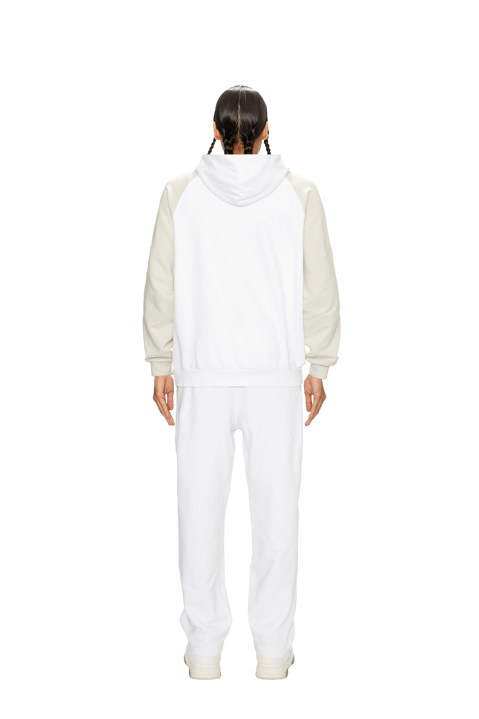 A person with long dark braids faces away, wearing the 6PM 2-TONE HOODIE WHITE paired with matching white pants and shoes, set against a plain white background.